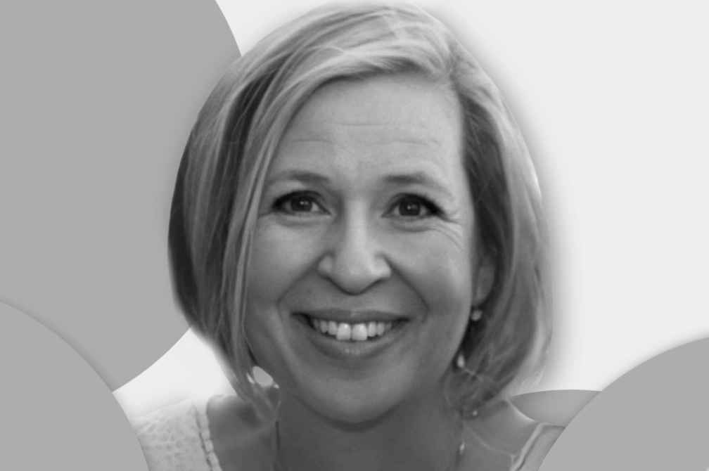 Black and white portrait of a smiling woman with short blonde hair.