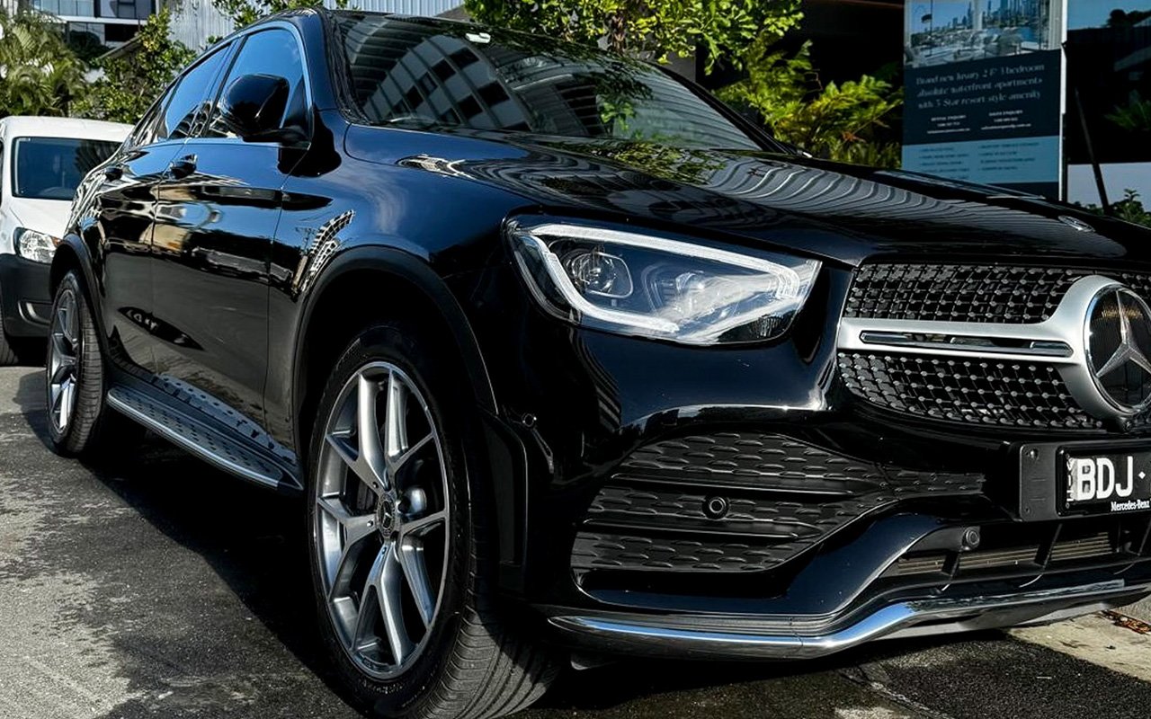 Black Mercedes-Benz SUV parked on a street, showcasing front grille and headlight.