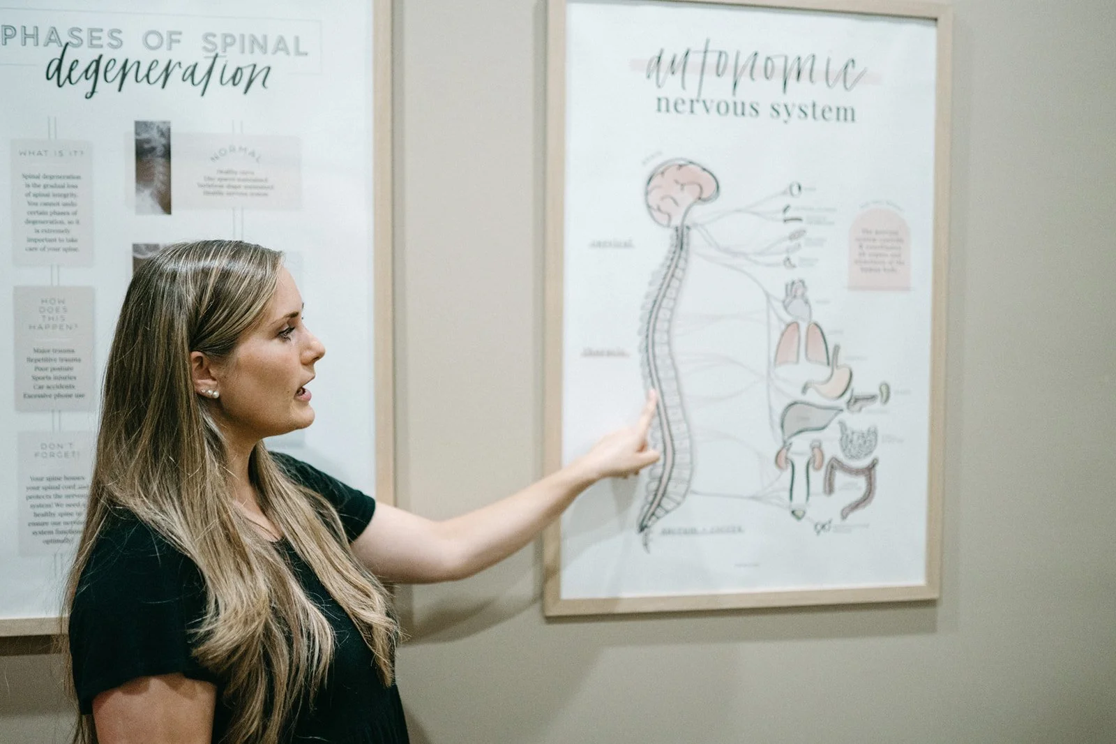 Dr. Anne Peters pointing at an educational poster of the autonomic nervous system and spinal cord connections at Hometown Chiropractic & Wellness in Nolensville, Tennessee