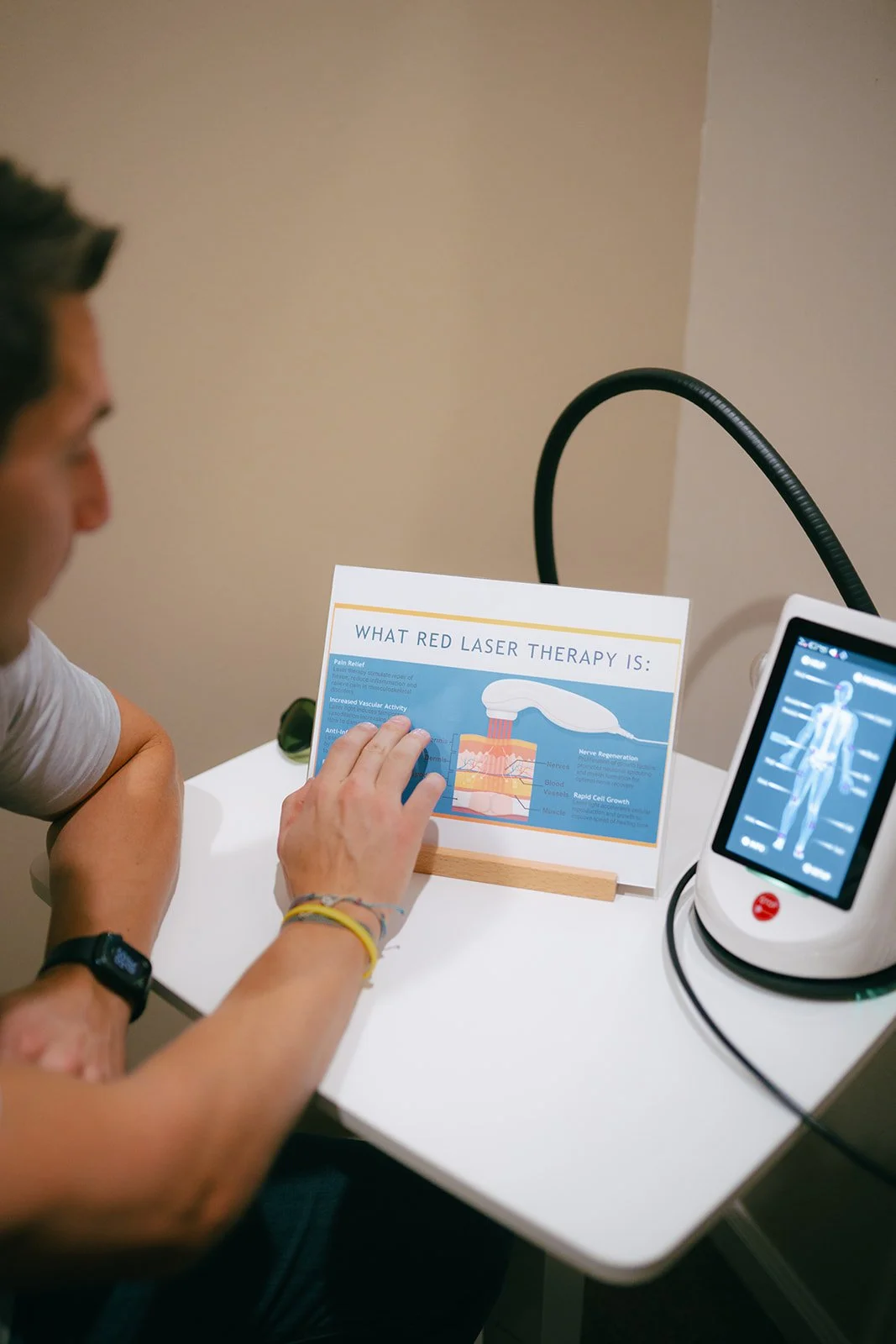 A person reviewing a flyer about red laser therapy, sitting at Hometown Chiropractic & Wellness in Nolensville Tennessee