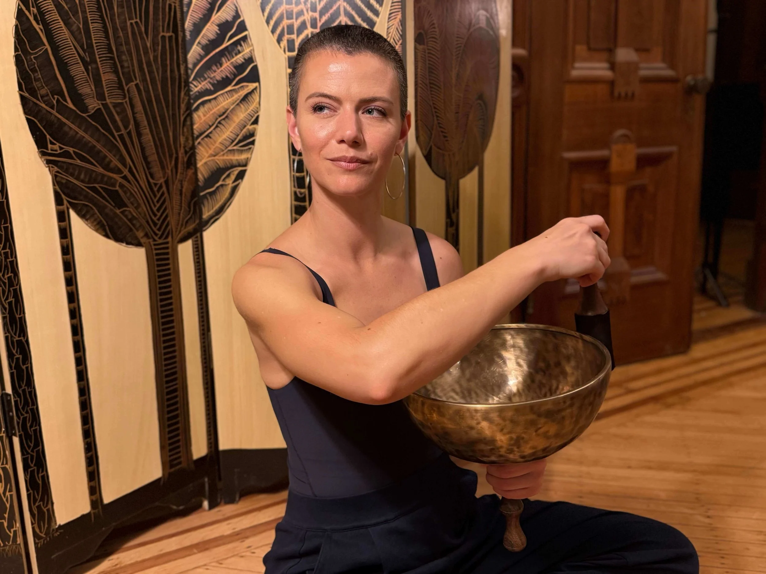 Practitioner using singing bowl for sound healing therapy to promote relaxation and energy balance