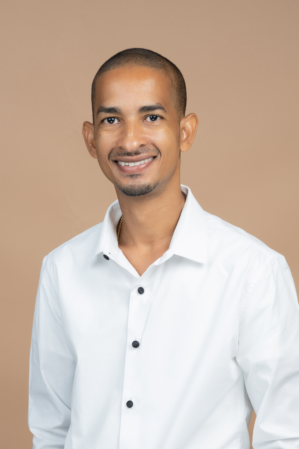 Alesta Deslandes relationship coach smiling confidently in white shirt against beige background.