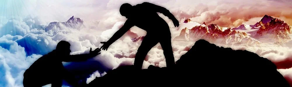 A person sitting on a bench with arms stretched forward, head bowed, and hands resting on knees, surrounded by four other hands touching shoulders, head, and arms in a supportive gesture.