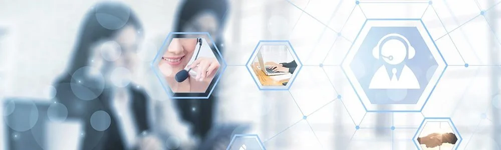 Two women sit at a table reviewing and discussing paperwork, with one woman holding a pen and the other woman resting her arms on the table.