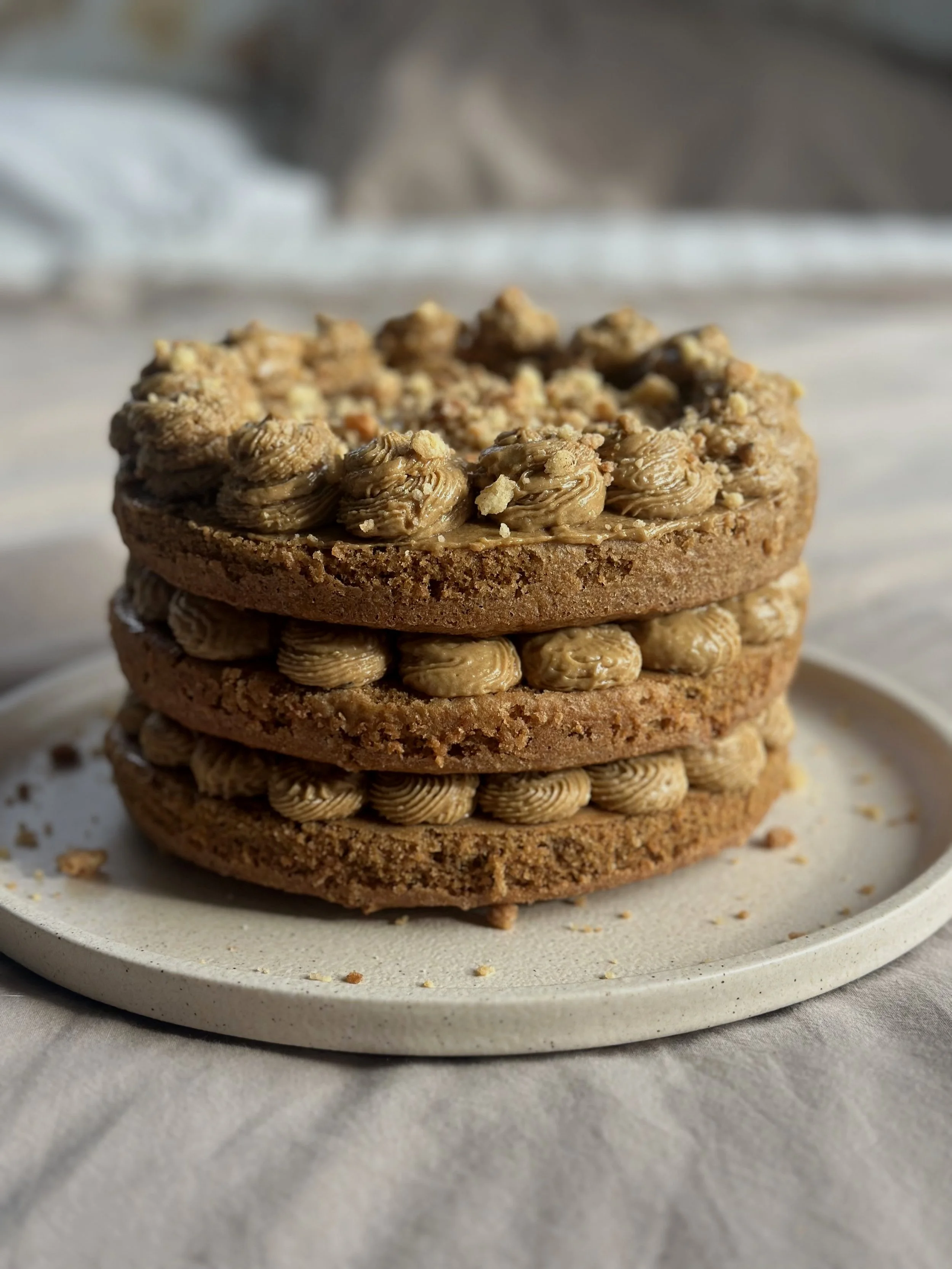 Stack of three cookies with nutella and crushed nuts on a white plate.