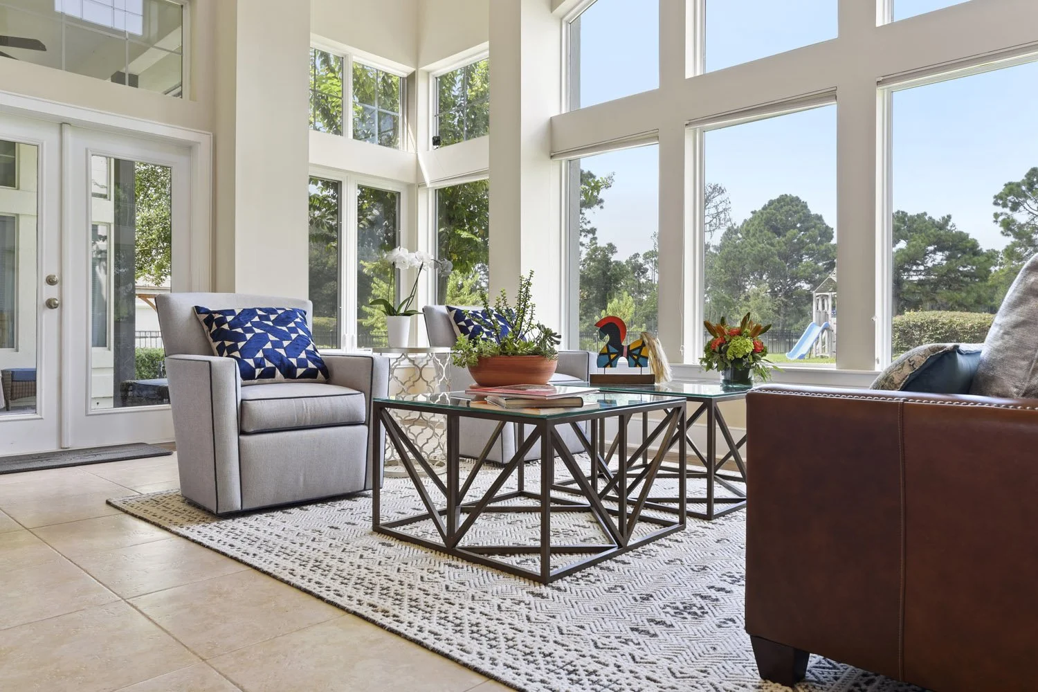 Leather sofa and gray armchairs facing two-story windows