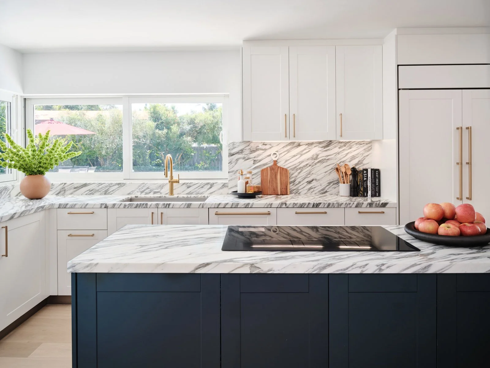 Navy kitchen island with marble top and bowl of fruit