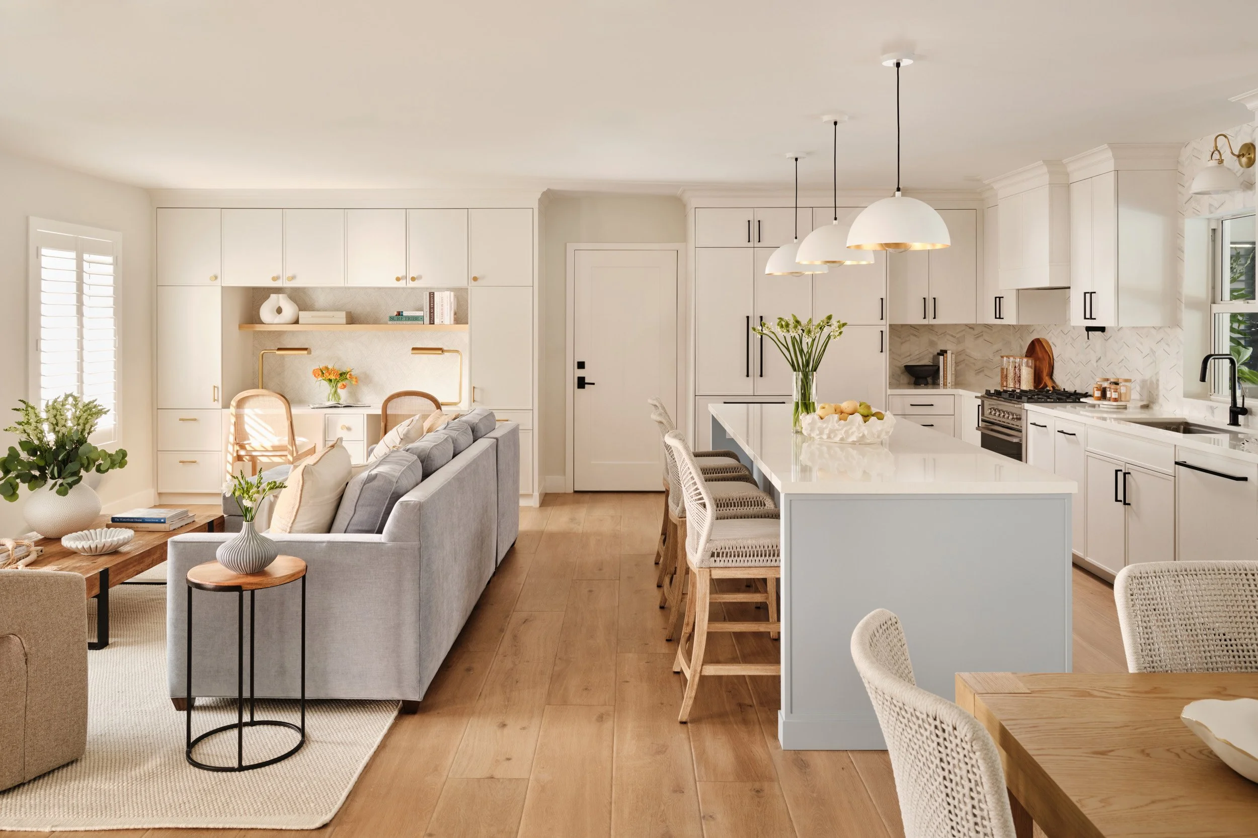 Open-plan kitchen and living room with white cabinetry and pendant lights