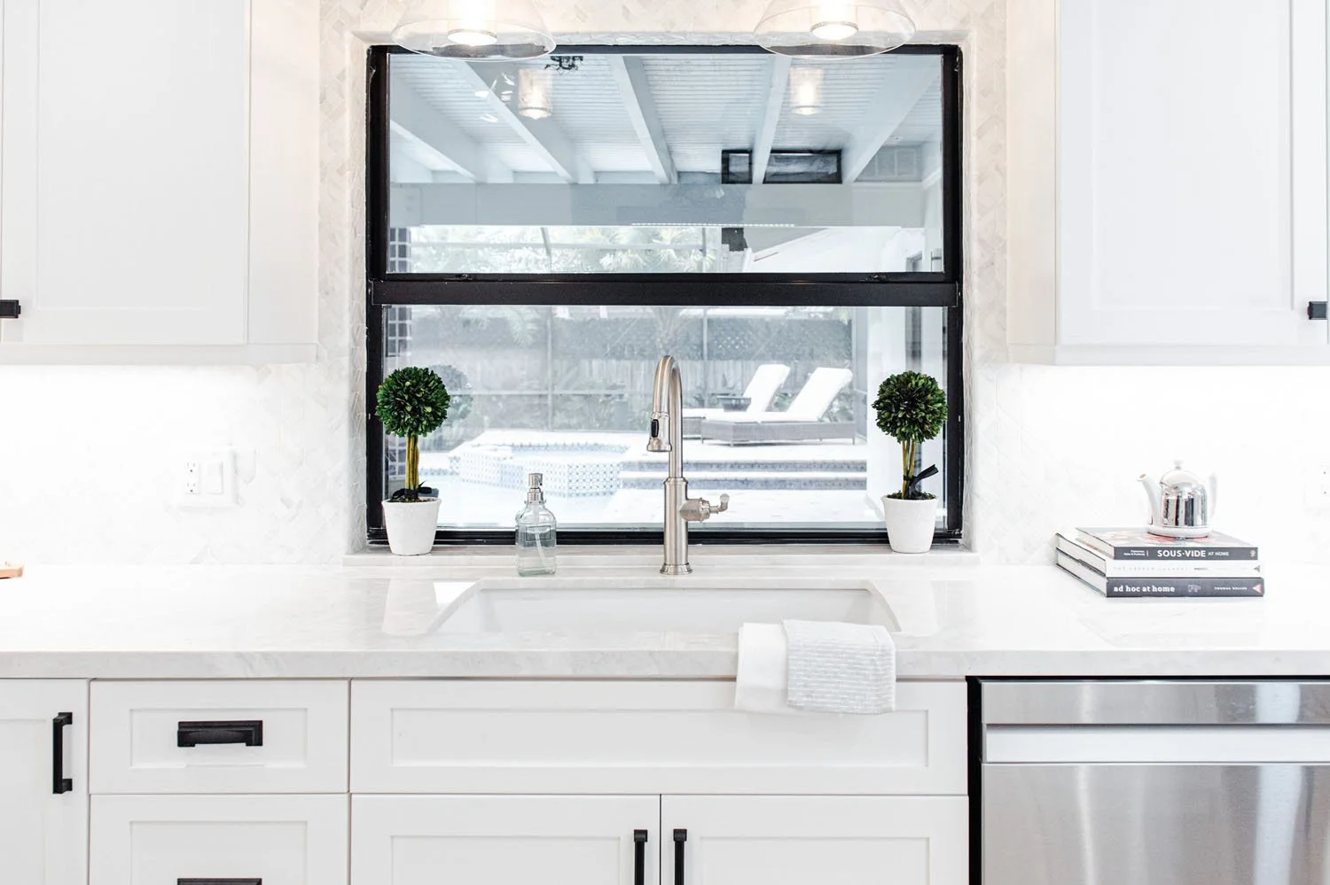 Kitchen sink under a black-framed window with quartz counters