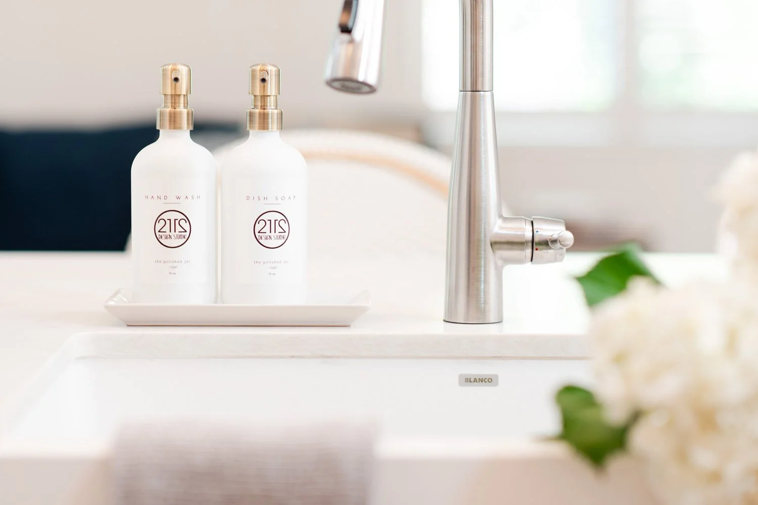 White soap dispensers beside a kitchen faucet