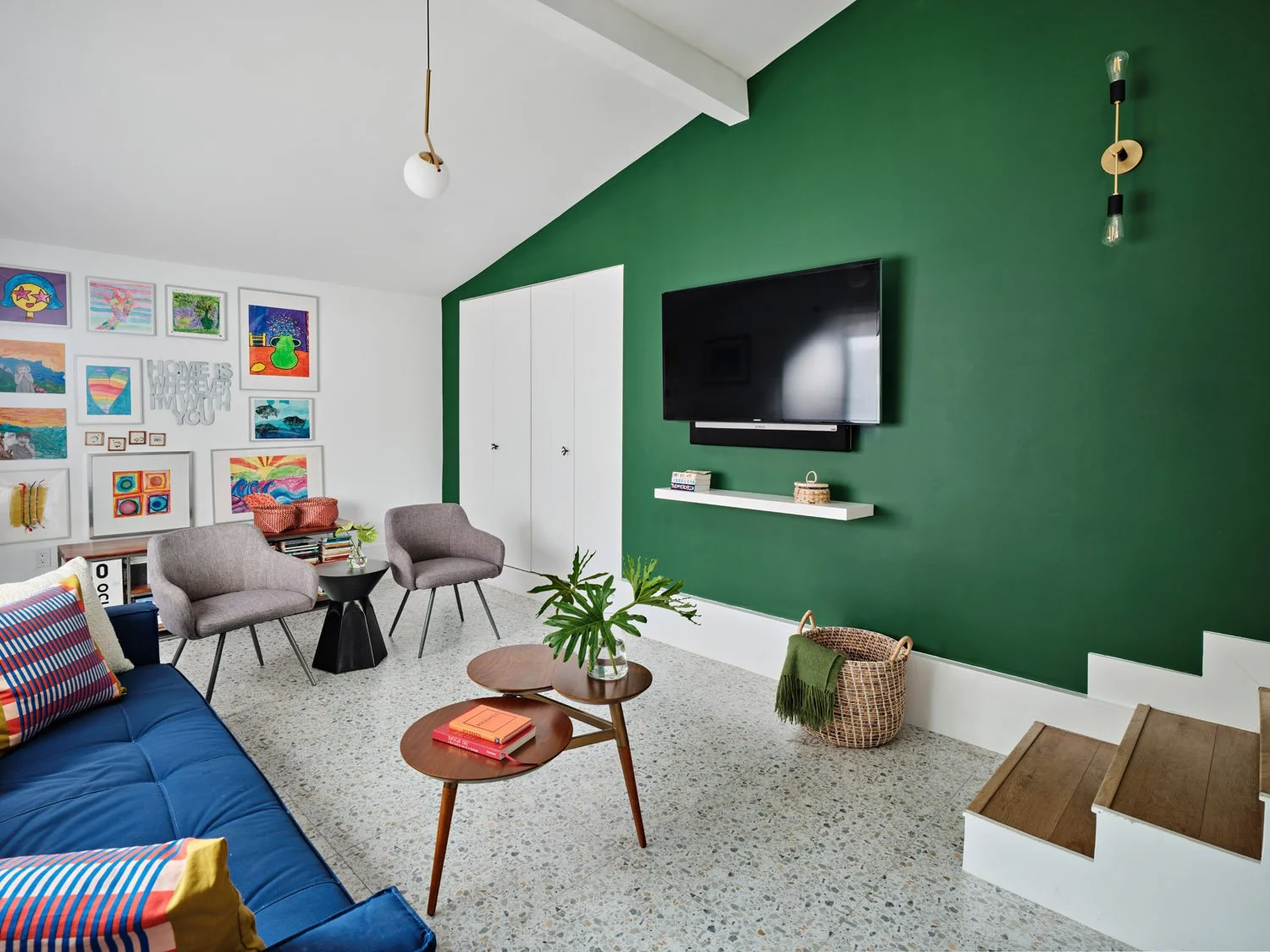 Family room with green accent wall, wall-mounted TV and gray chairs