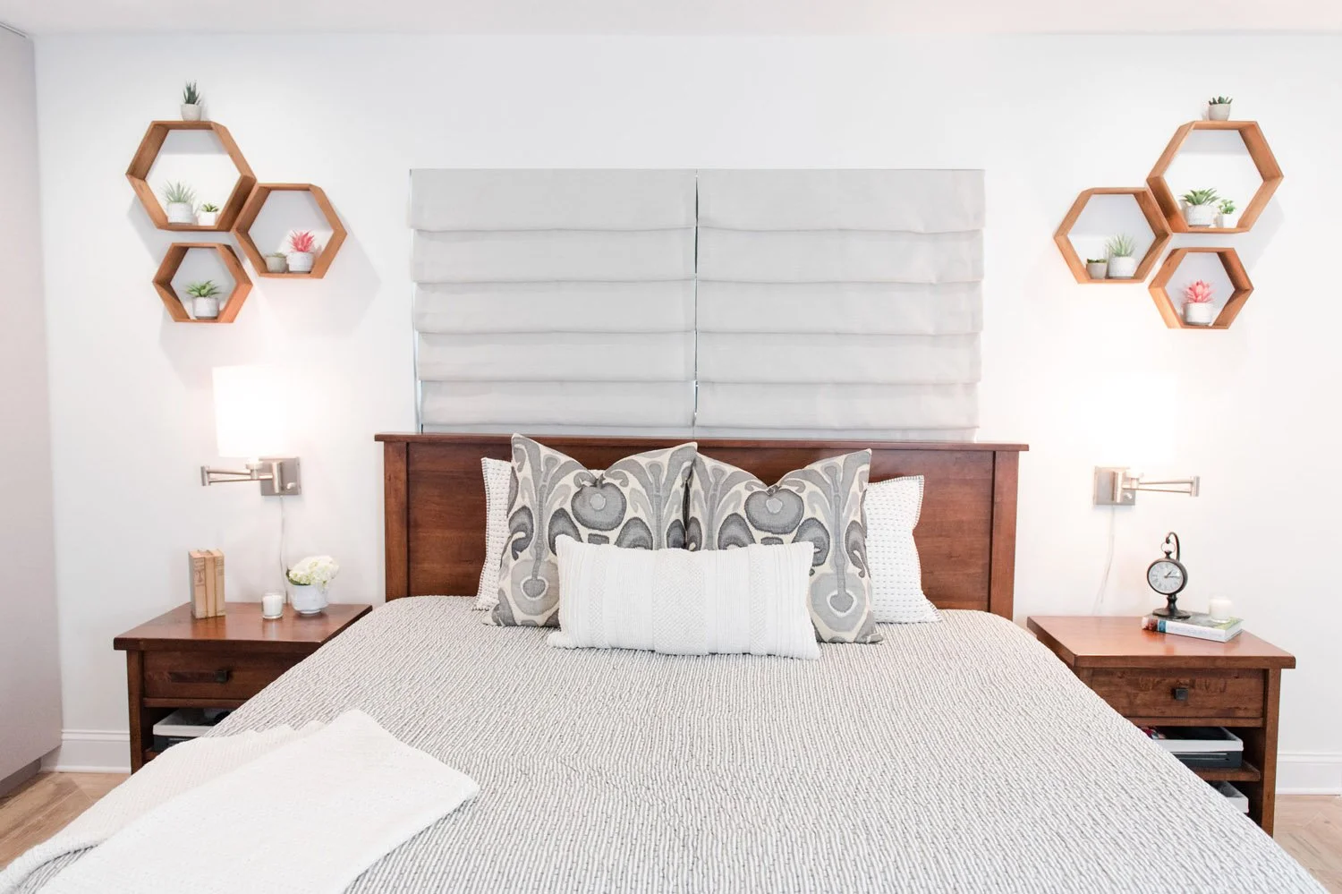 Bed with gray paneled headboard flanked by hexagon wall shelves