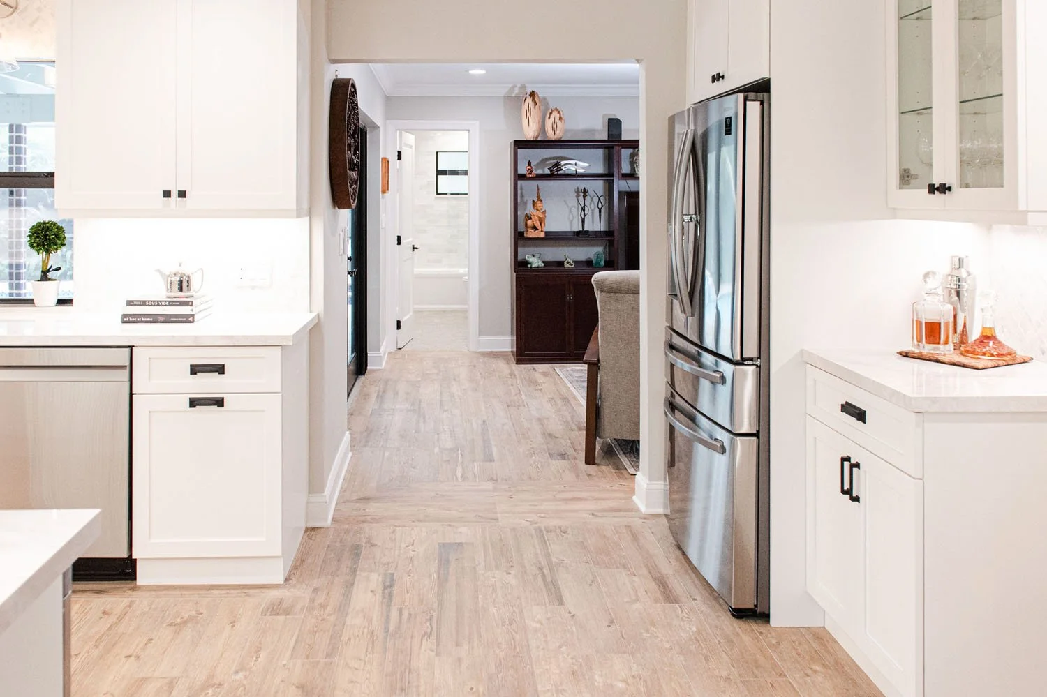 White kitchen with stainless refrigerator and wood-look tile floor