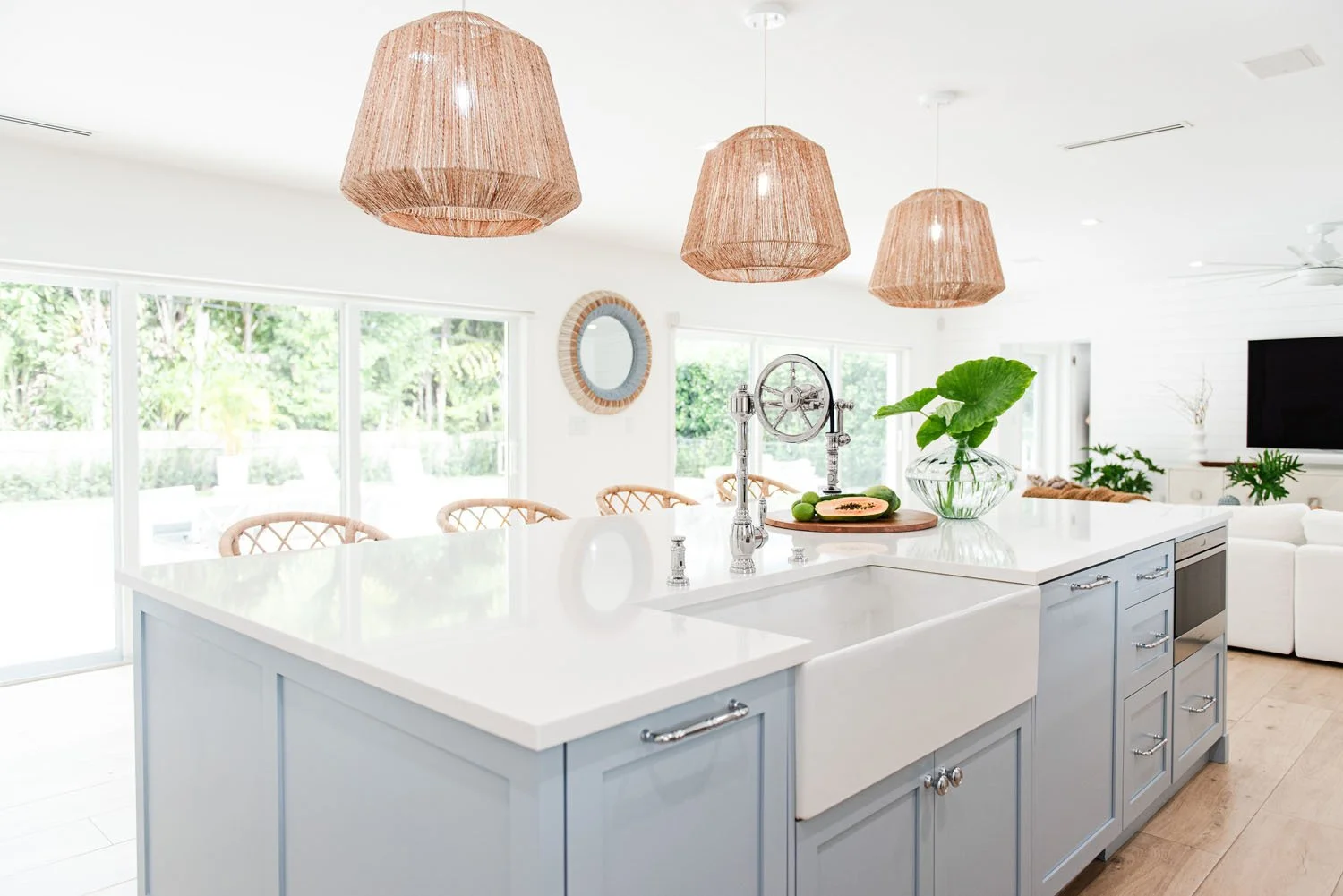 Light blue kitchen island with farmhouse sink and rattan pendants