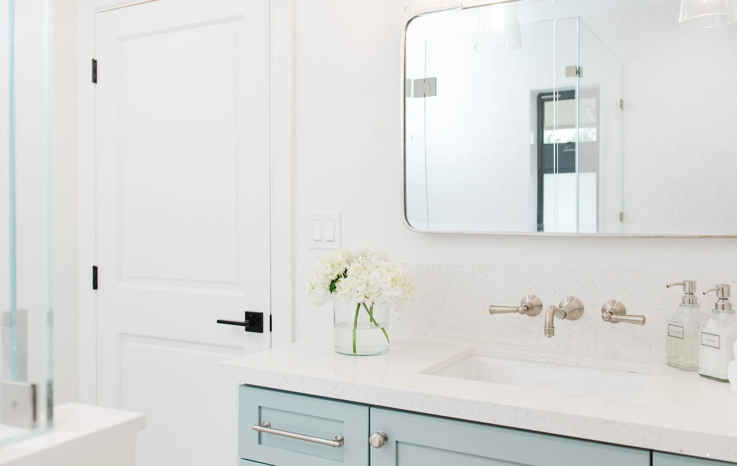 Light blue vanity with wall-mounted faucet and rounded mirror