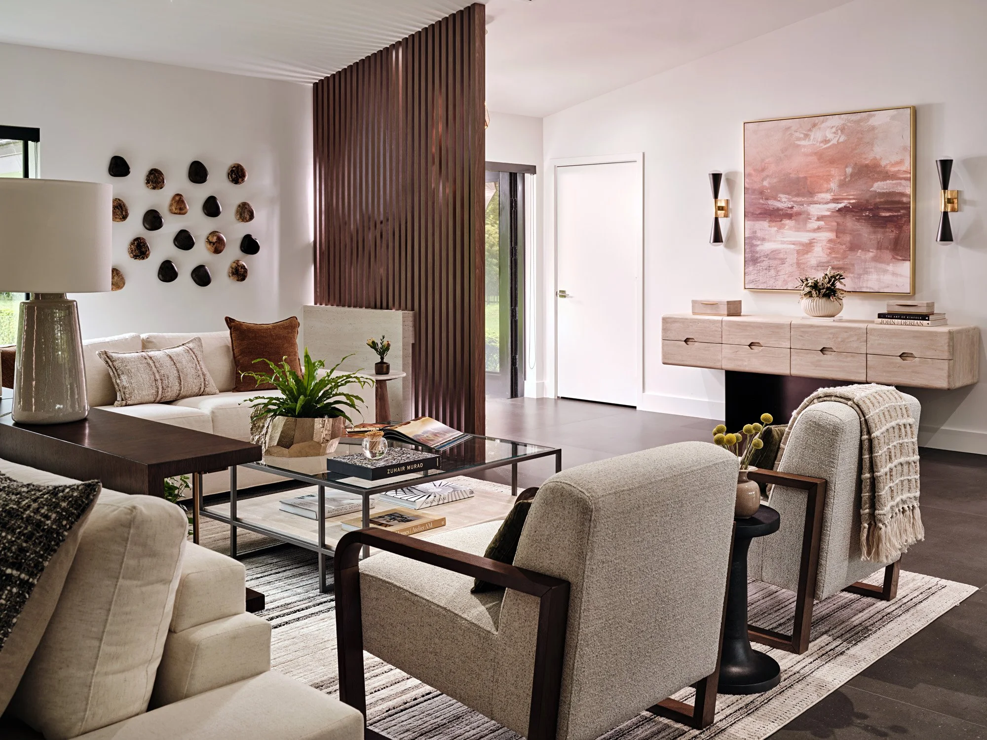 Living room with armchairs, glass coffee table and console with abstract art