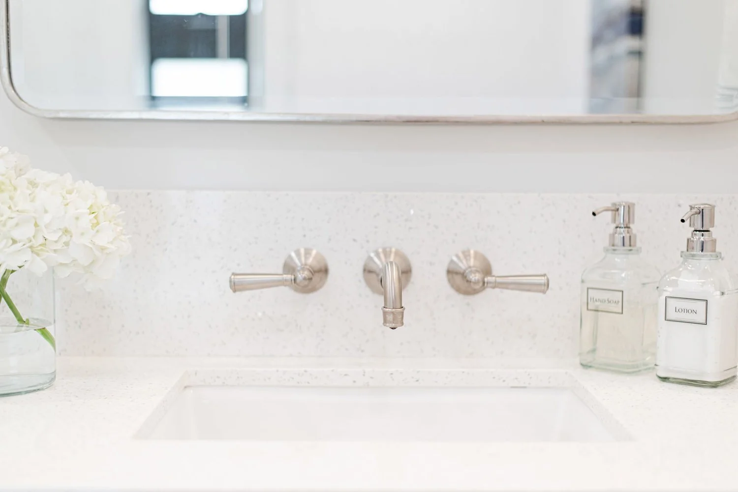 Wall-mounted faucet over an undermount sink with soap dispensers