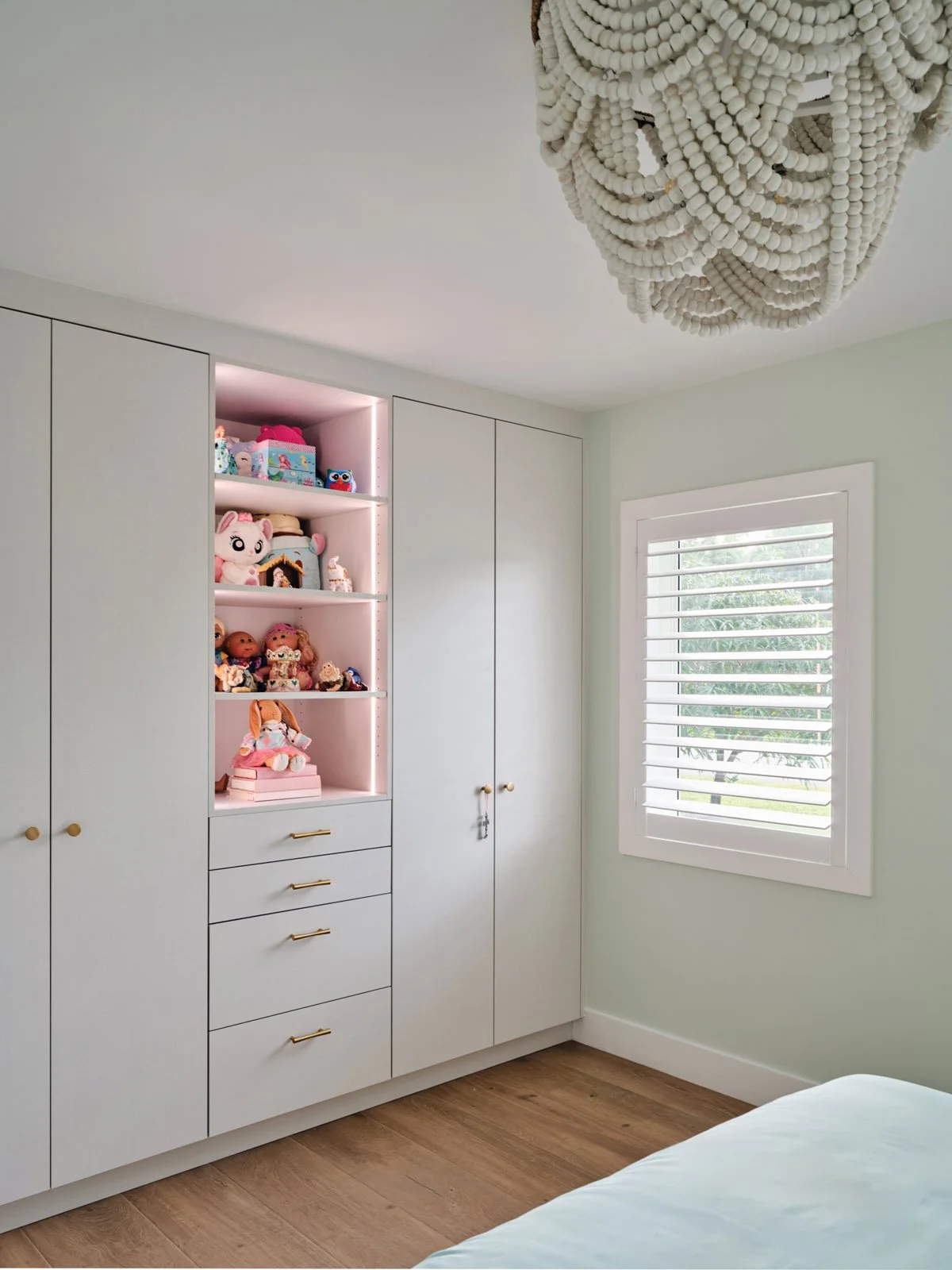 Built-in closet with pink-lit shelves and white drawers