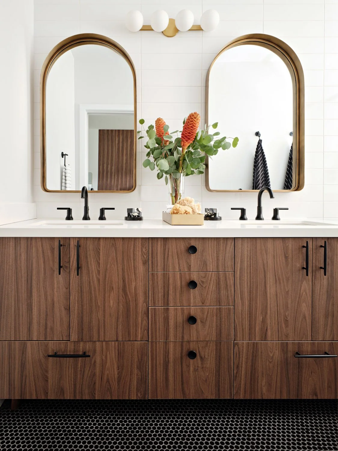 Bathroom with walnut double vanity and brass arched mirrors