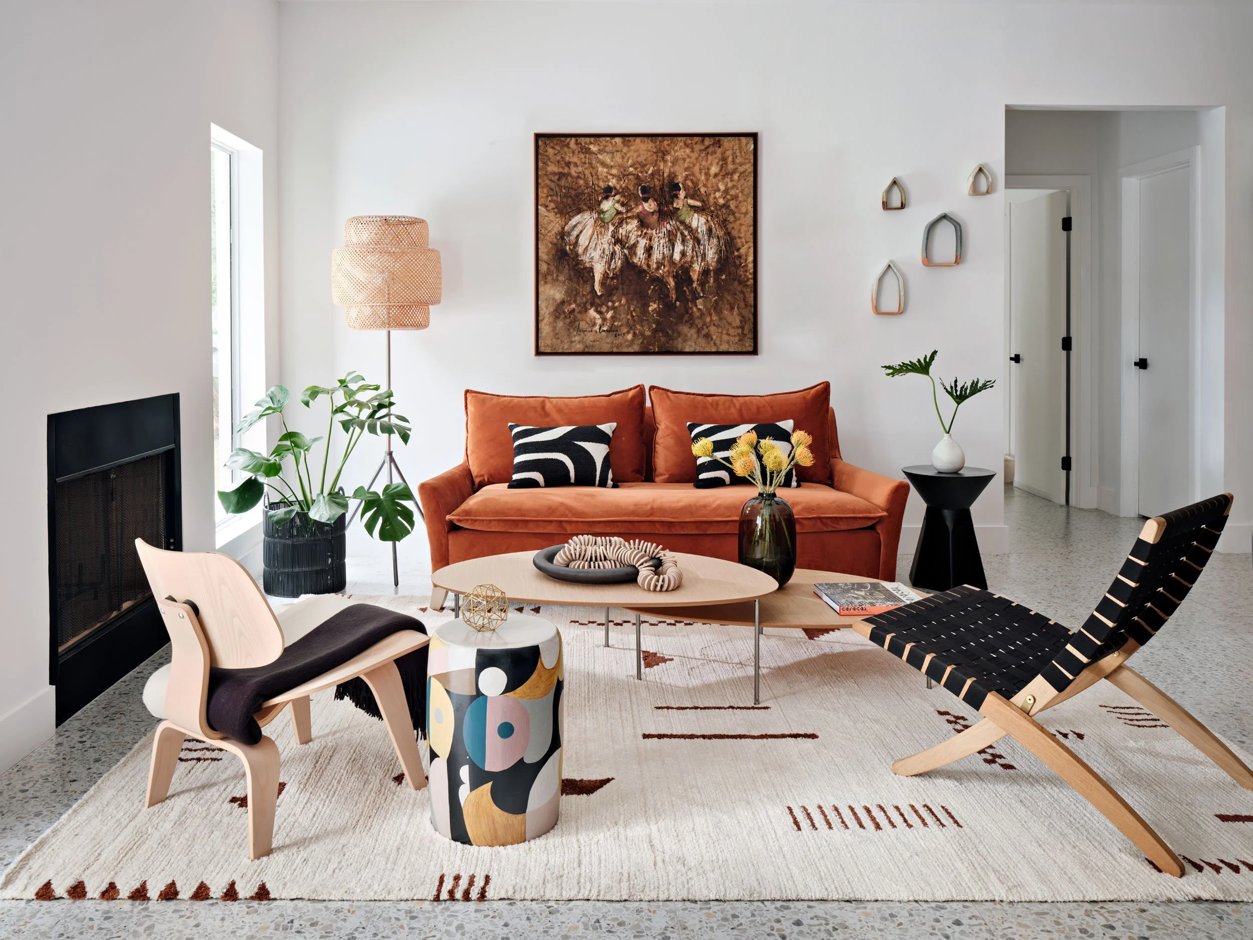 Living room with rust velvet sofa, molded plywood lounge chairs and patterned rug
