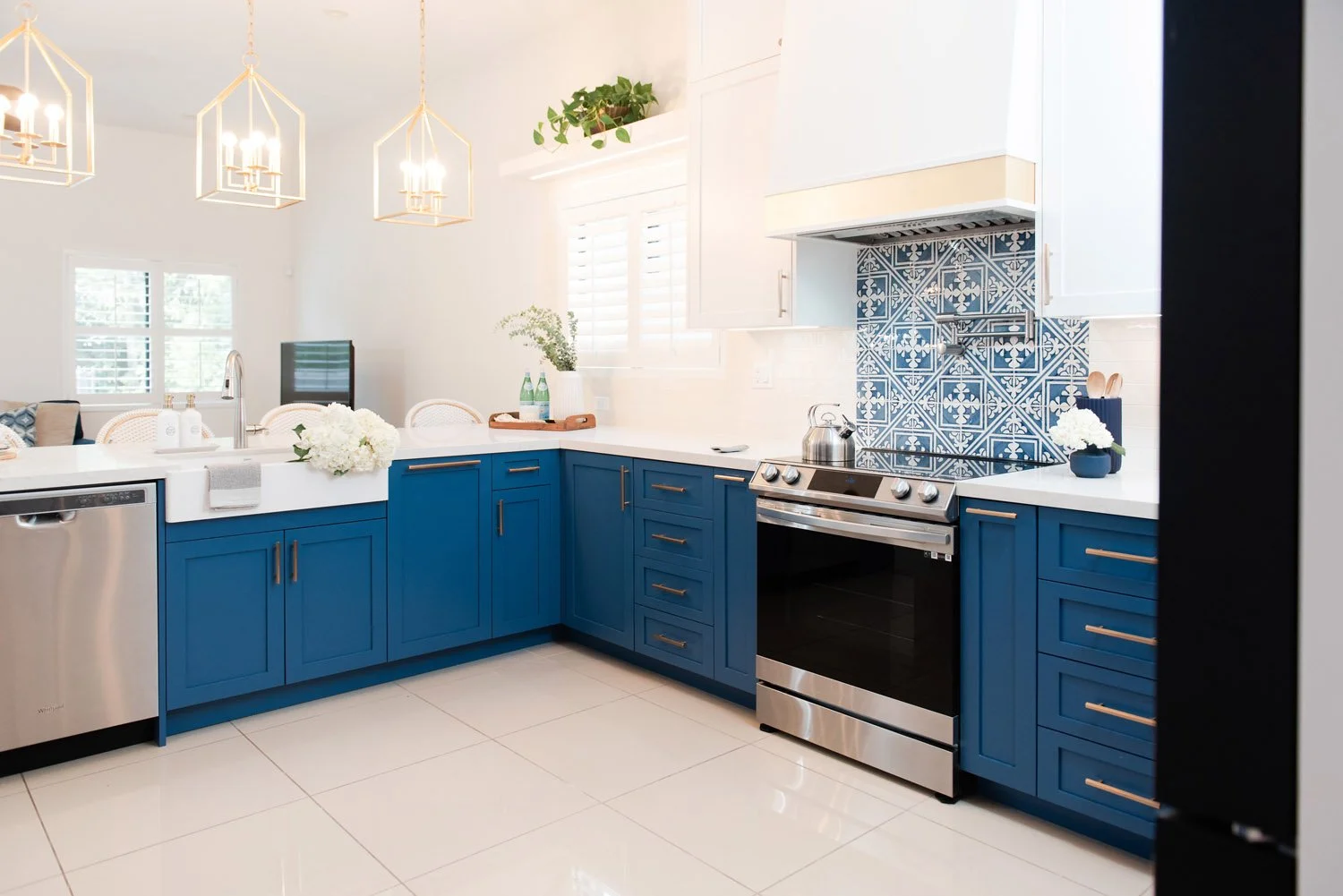 L-shaped navy kitchen with white counters and stainless appliances
