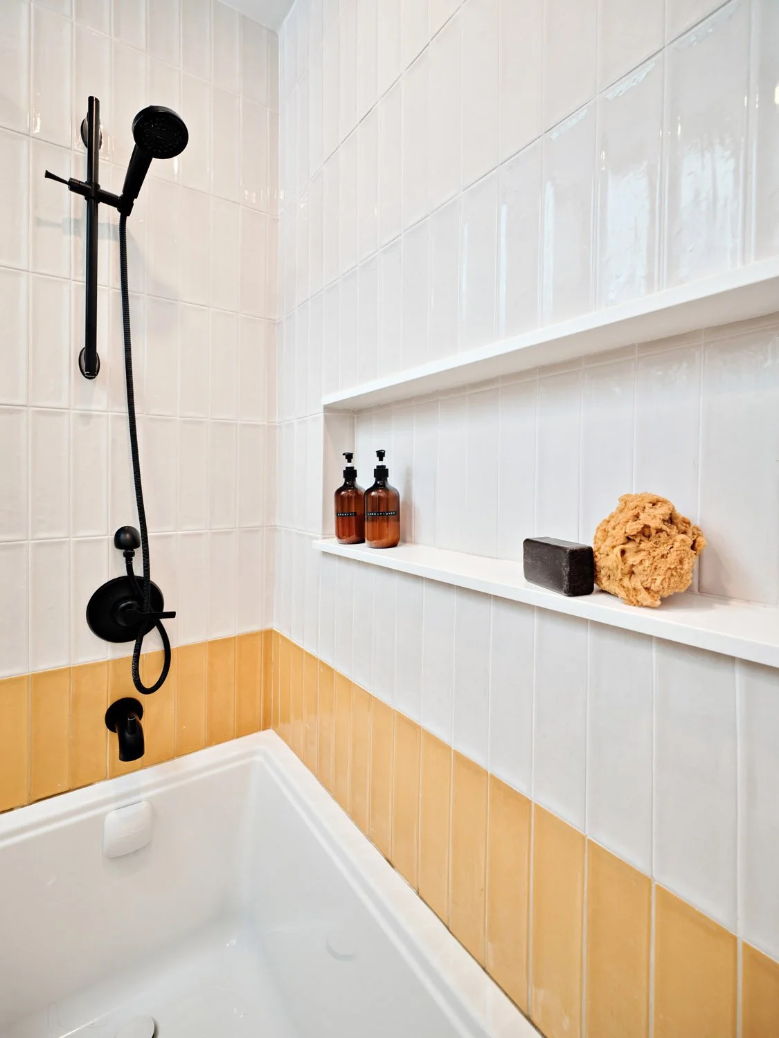 Bathtub with yellow tile, white wall tile and black shower fixtures