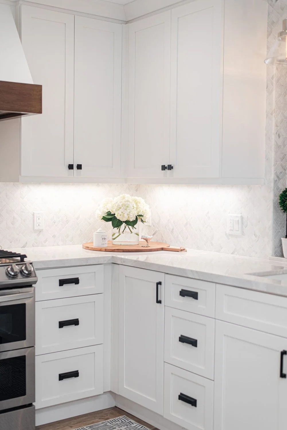 White kitchen corner with shaker cabinets and black hardware