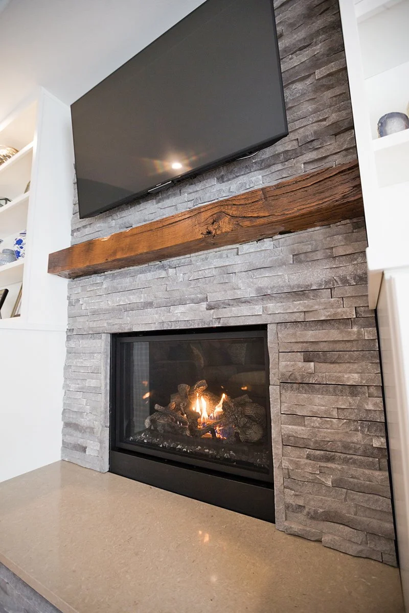 Stone fireplace with reclaimed wood mantel and mounted TV
