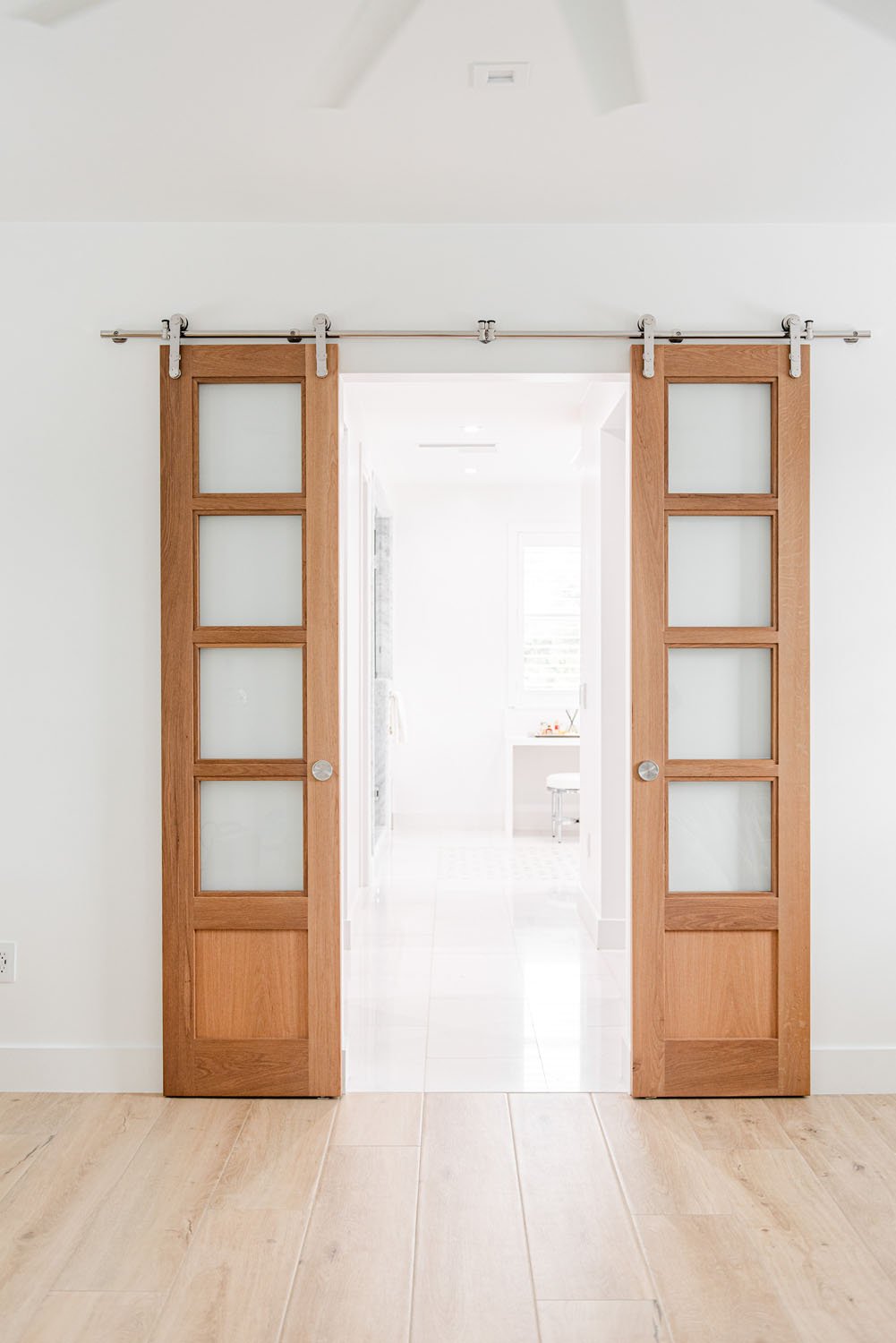 Wood French barn doors opening to a white hallway
