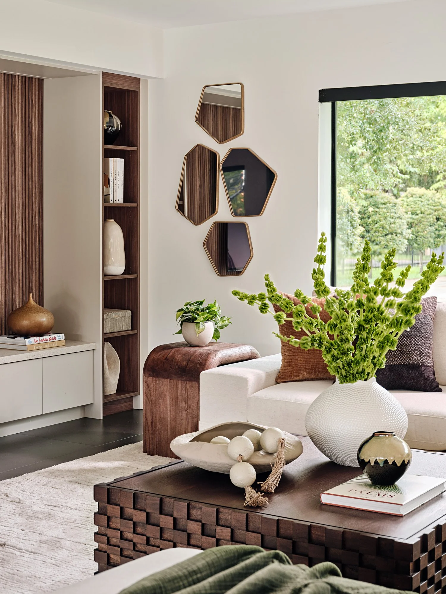 Seating area with walnut shelving, hexagon mirrors and white flowers