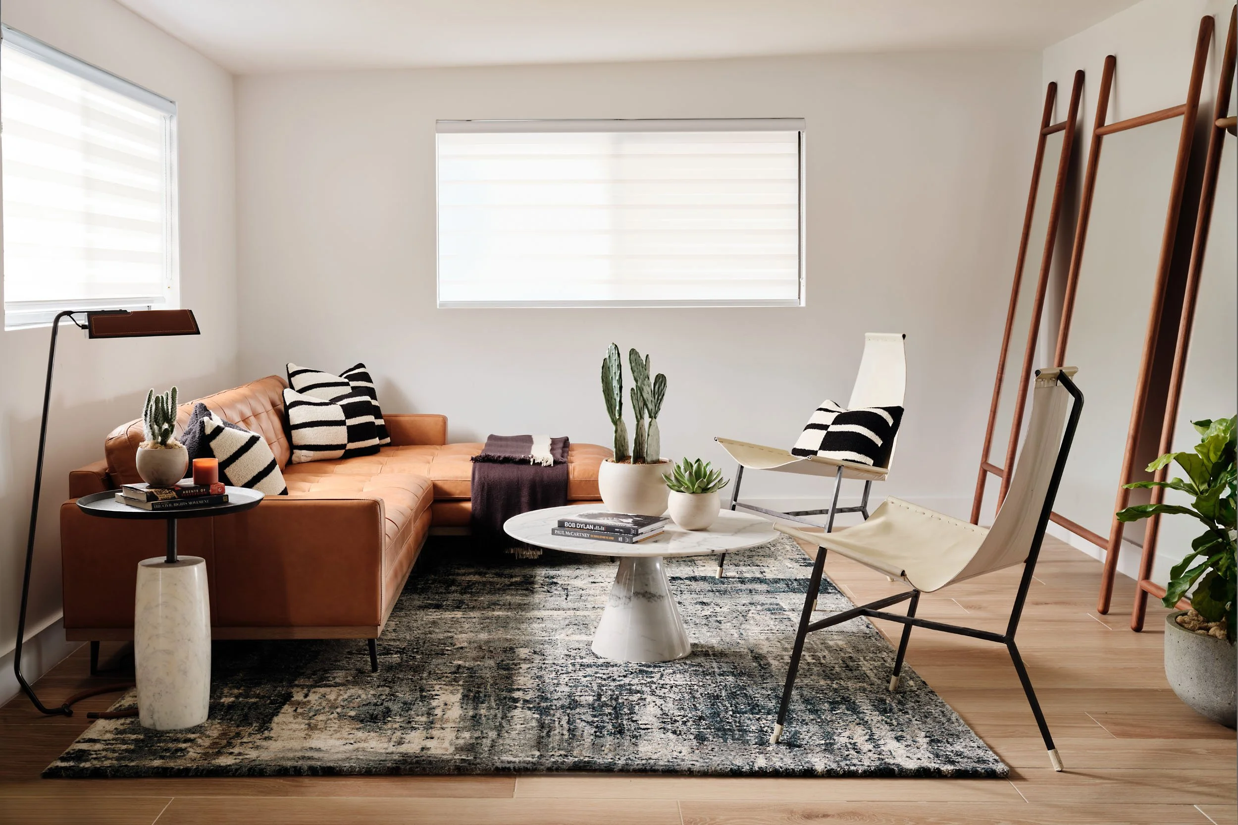 Living room with cognac leather sofa, round marble coffee table and abstract rug