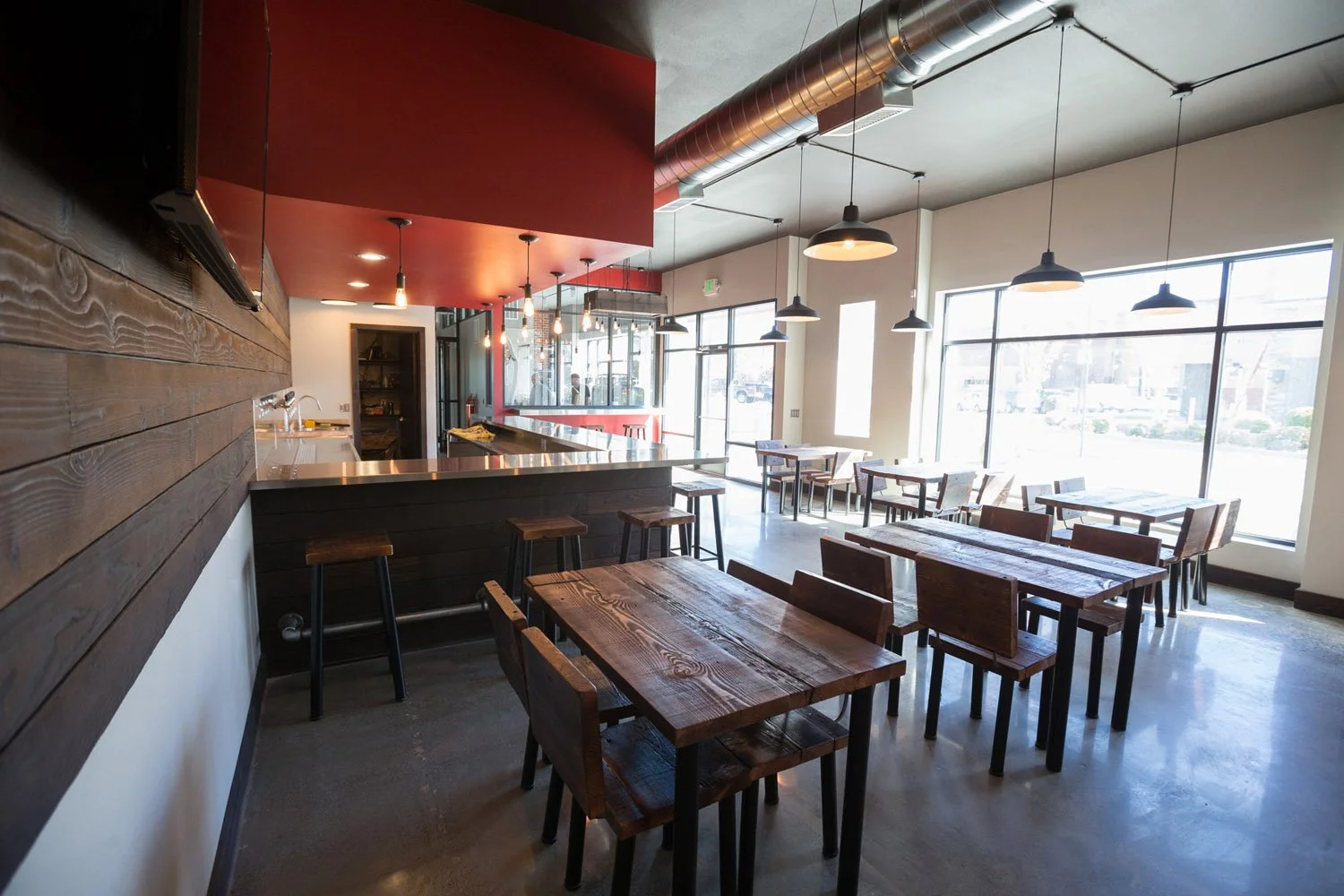 Taproom with wood communal tables and pendant lights