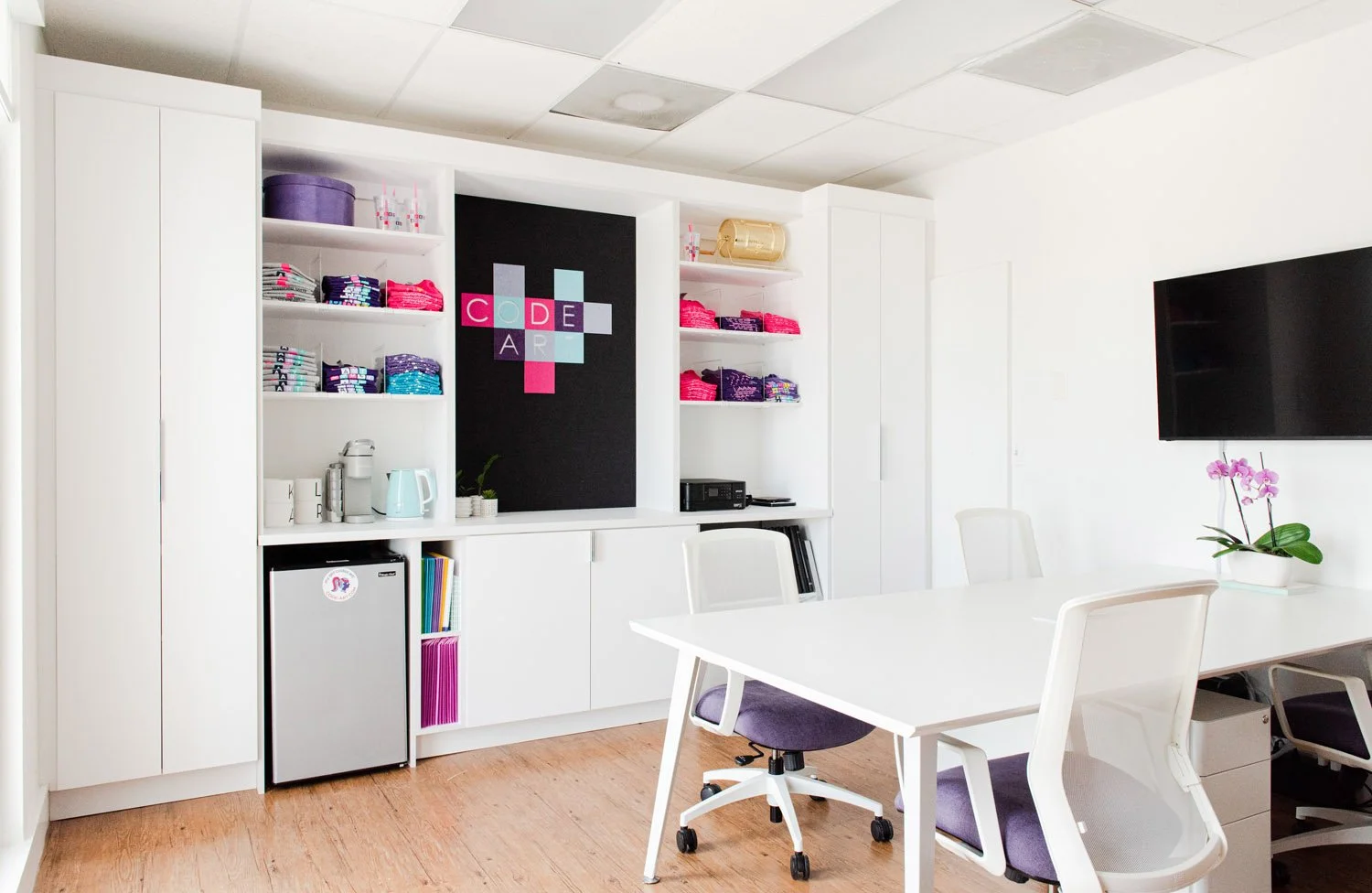 Office with white desk, wall-mounted TV and built-in storage