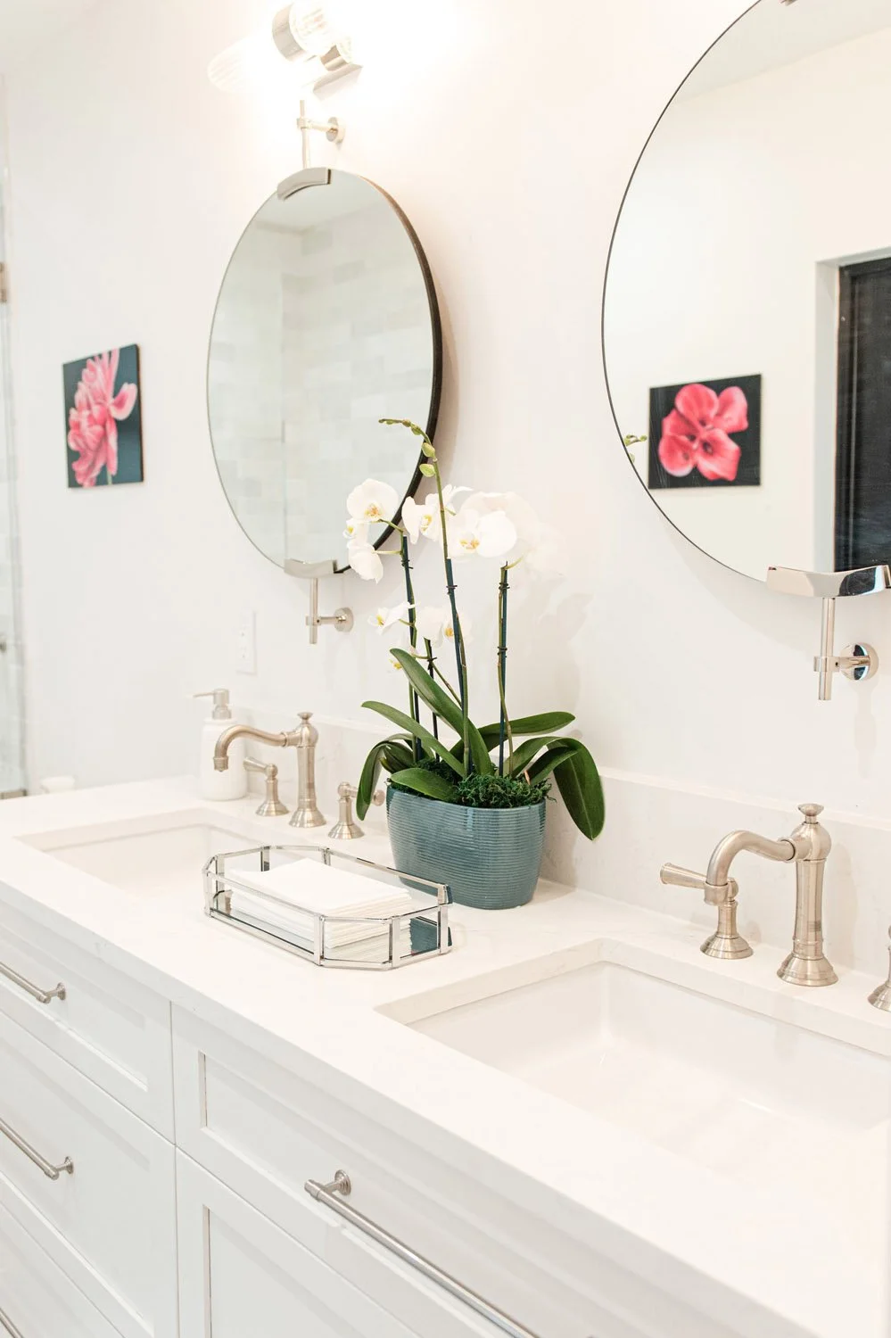 Double vanity with round mirrors and pink artwork