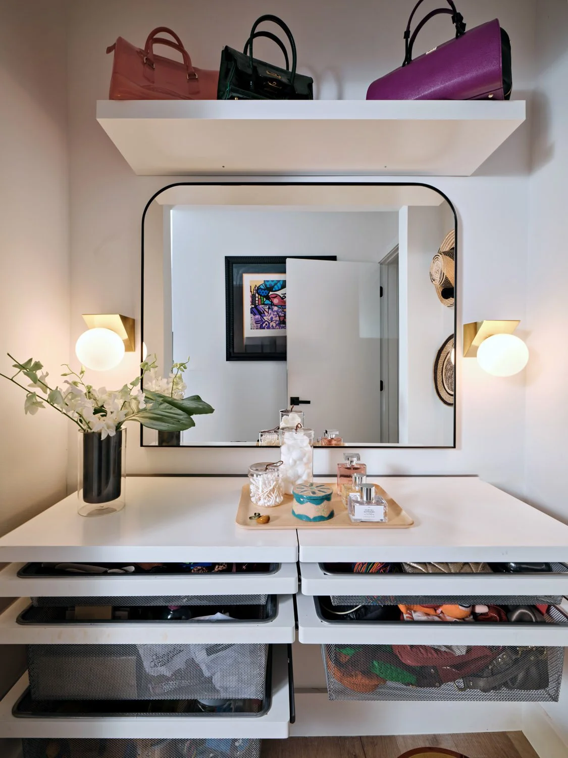 White vanity with rounded mirror, sconces and storage drawers