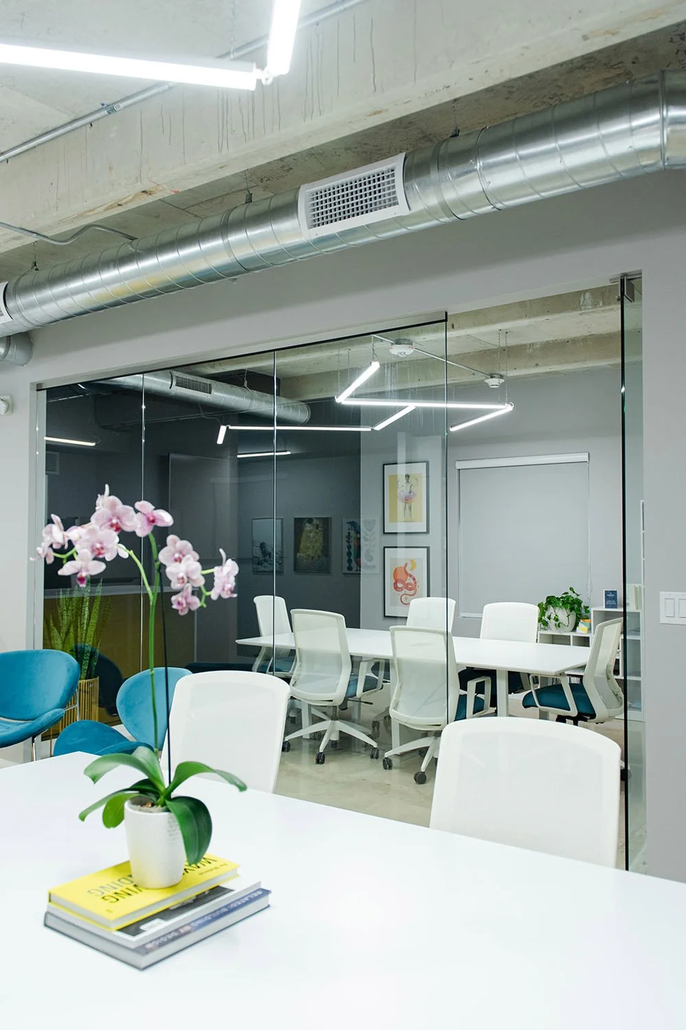 Glass conference room with white table and teal chairs