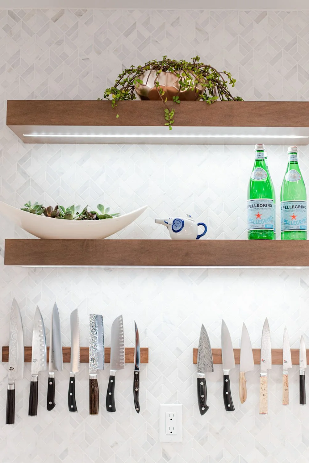 Floating walnut shelves with greenery above a knife strip