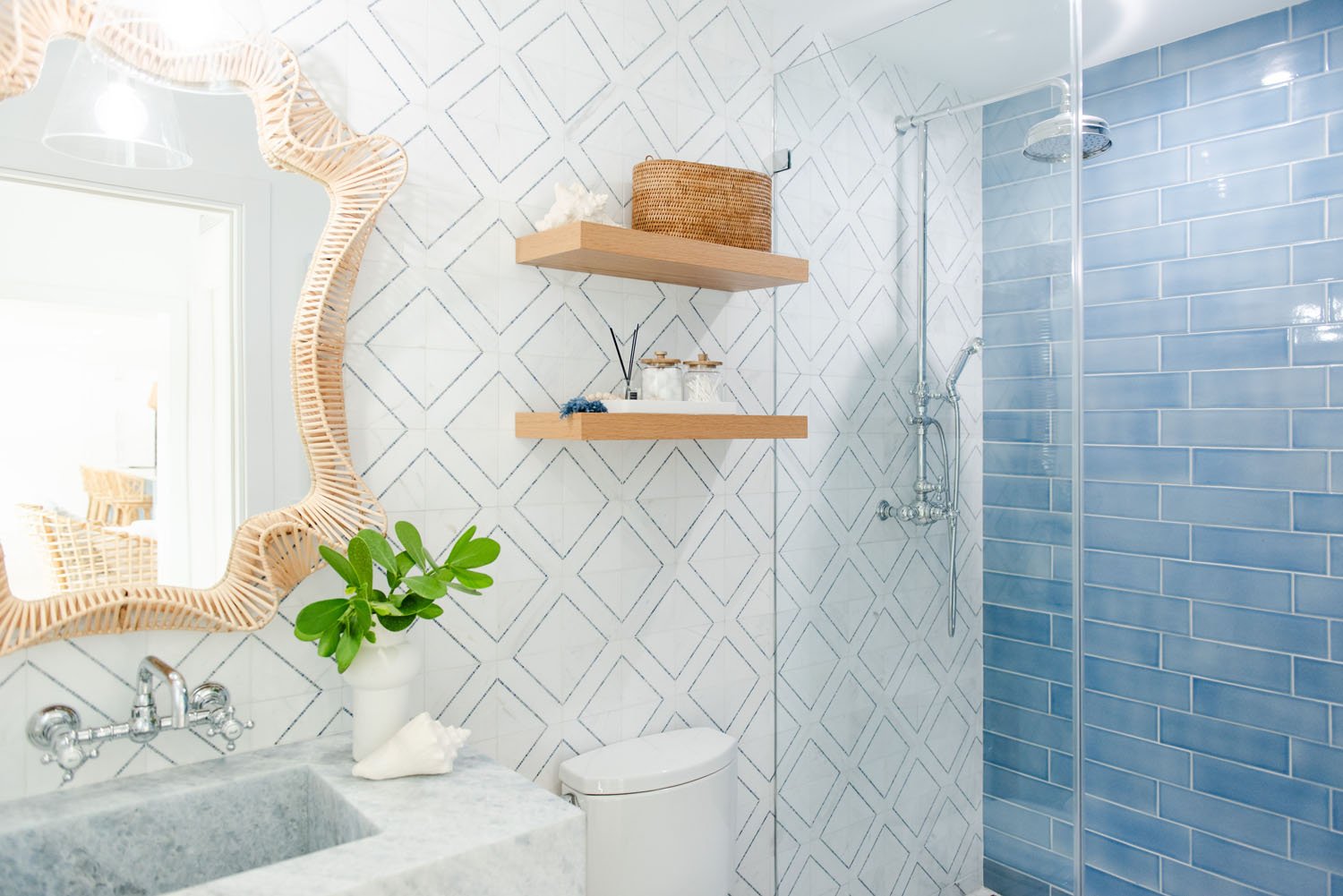 Bathroom with marble sink, rattan mirror and blue tile shower