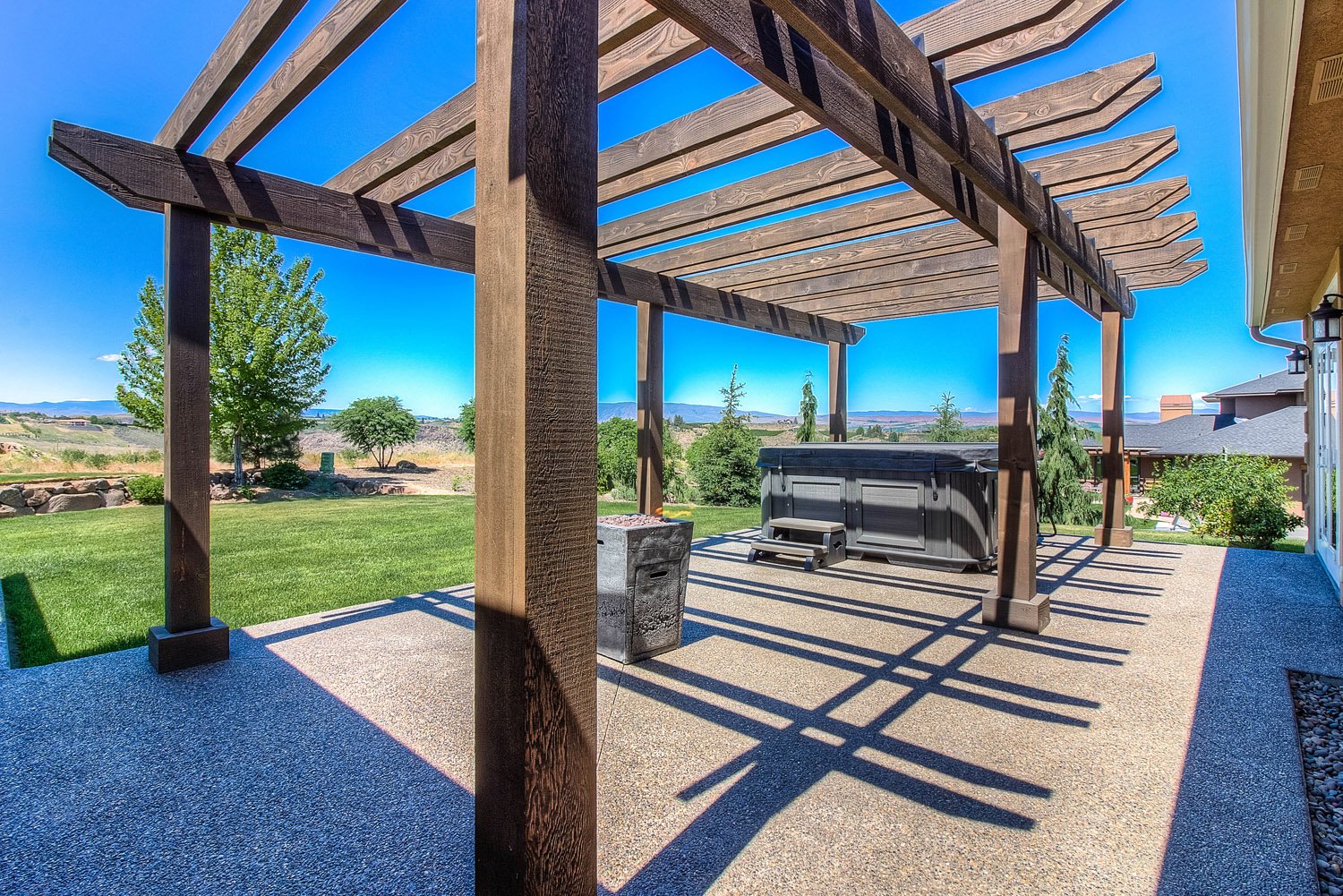 Wood pergola with hot tub and lawn beyond