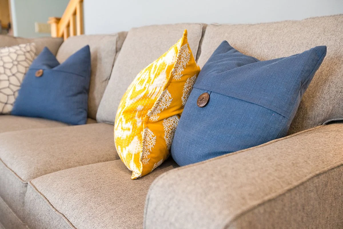 Gray sofa with yellow and navy throw pillows
