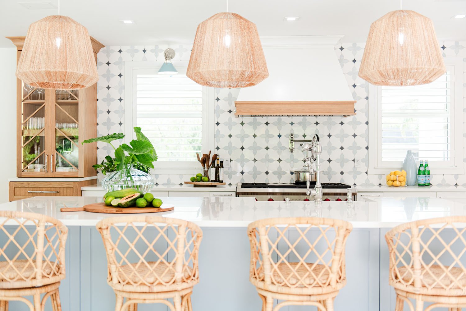 Kitchen island with rattan counter stools, woven pendant lights and patterned tile backsplash