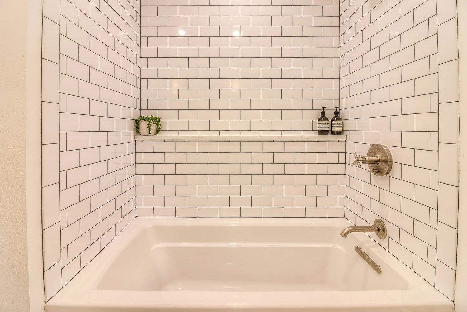 Soaking tub with white subway tile and dark grout