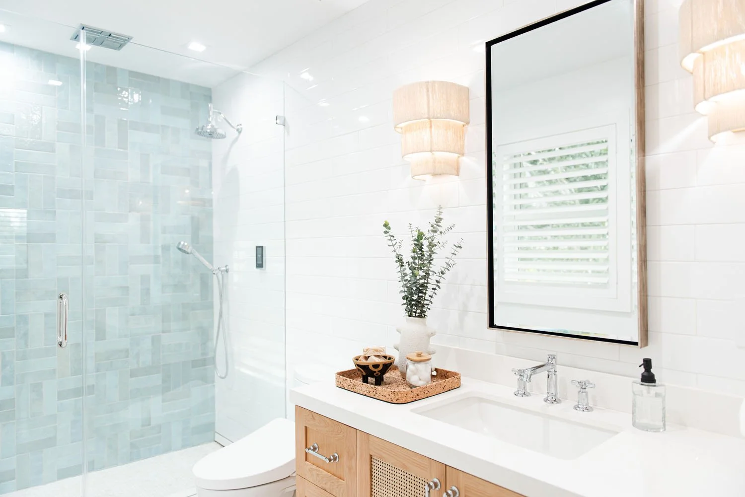 Bathroom with light wood vanity, black mirror and glass shower