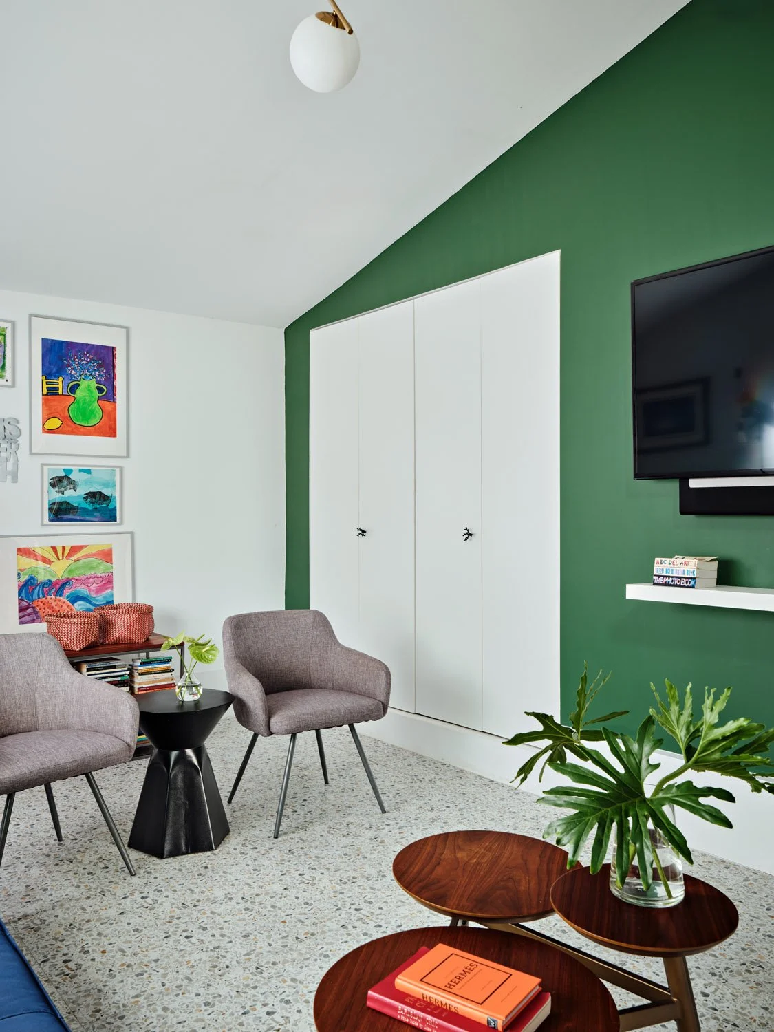 Gray lounge chairs with round wood table and green accent wall
