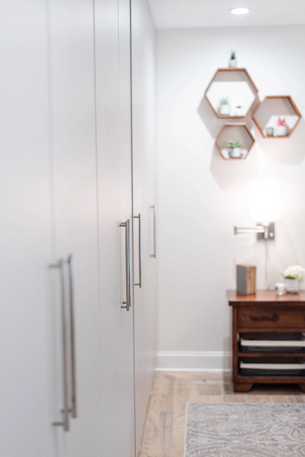 White wardrobe beside a nightstand and hexagon wall shelves