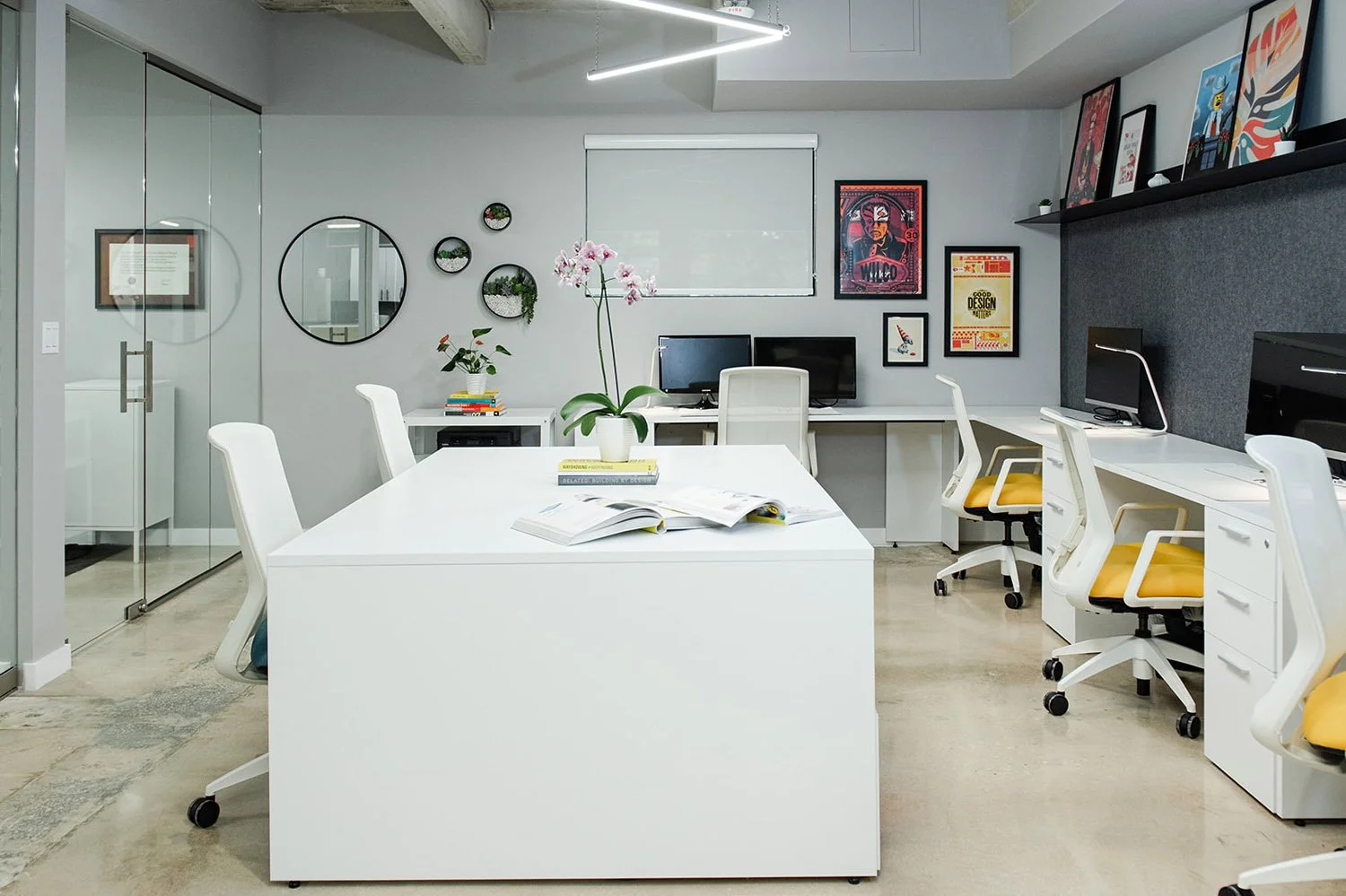 Long white work table with desks and framed posters beyond