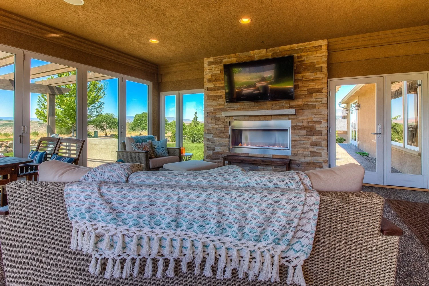 Sunroom with sofa, throw blanket and TV above a stone fireplace