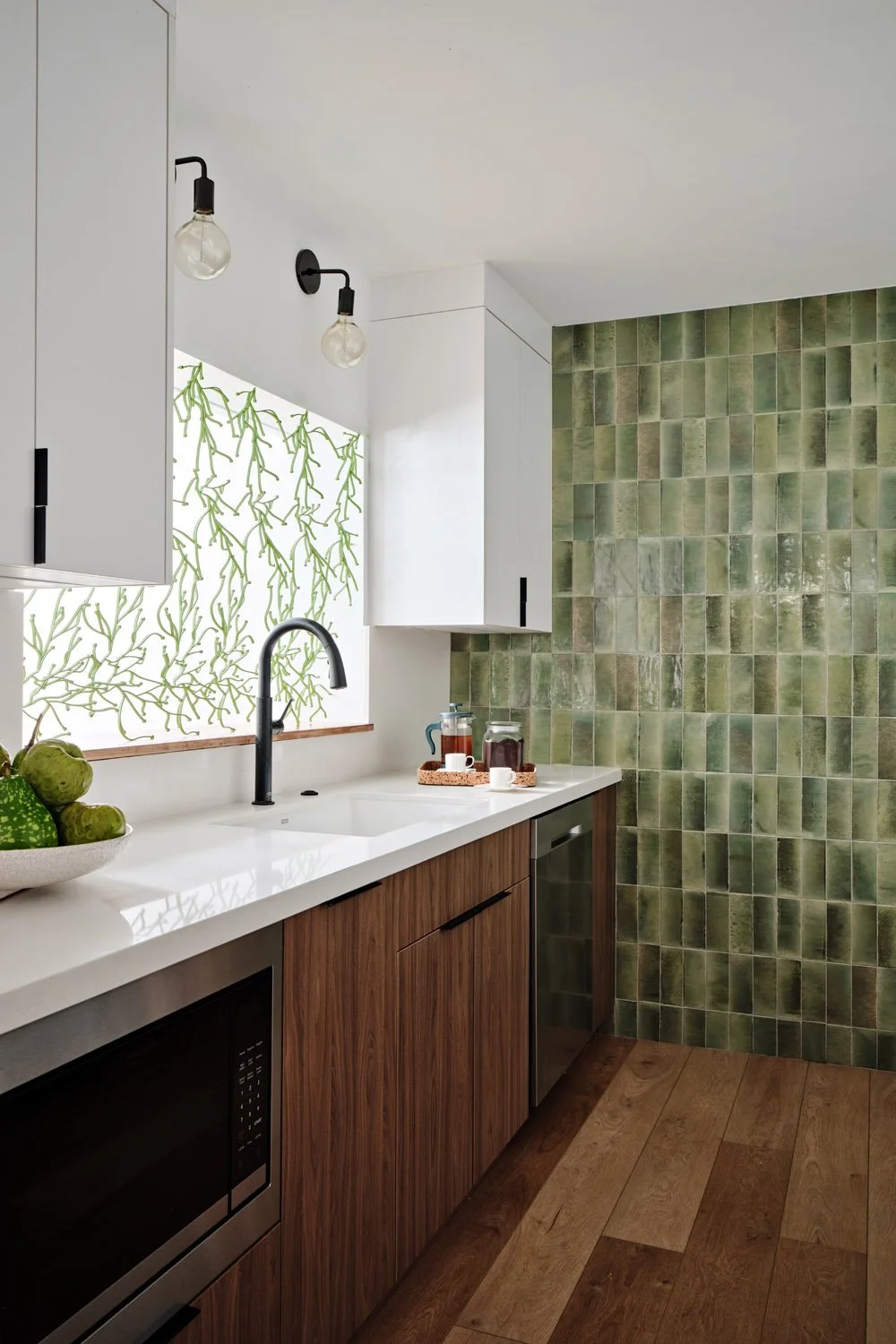 Kitchen sink with black faucet, green tile and walnut lower cabinets
