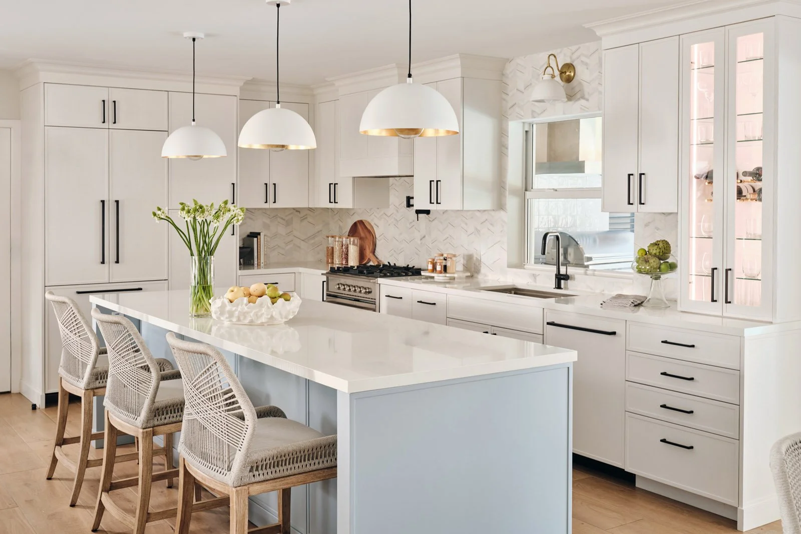 White kitchen with woven counter stools and dome pendants