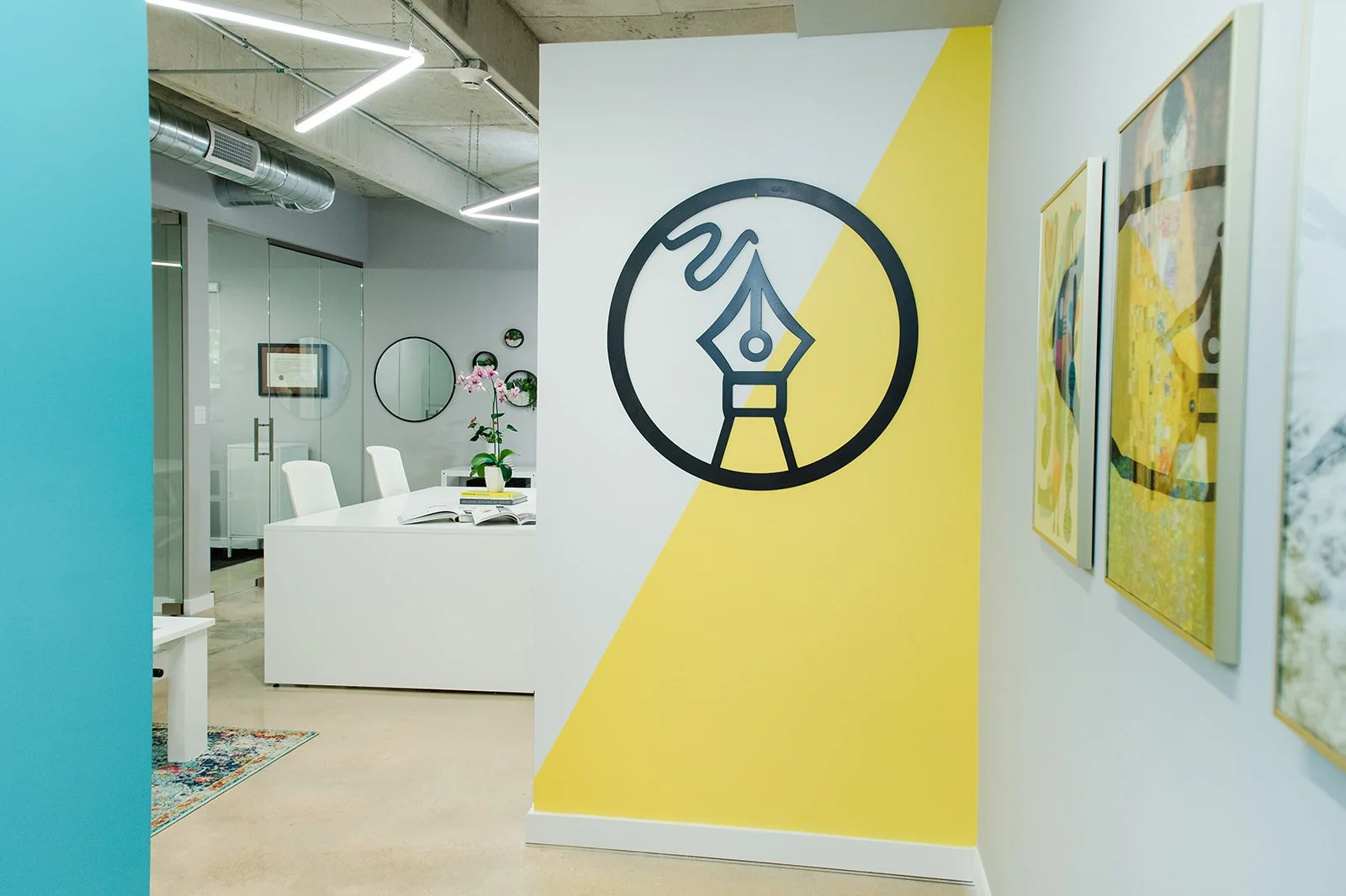Office entry with yellow and teal accent walls and pen nib logo